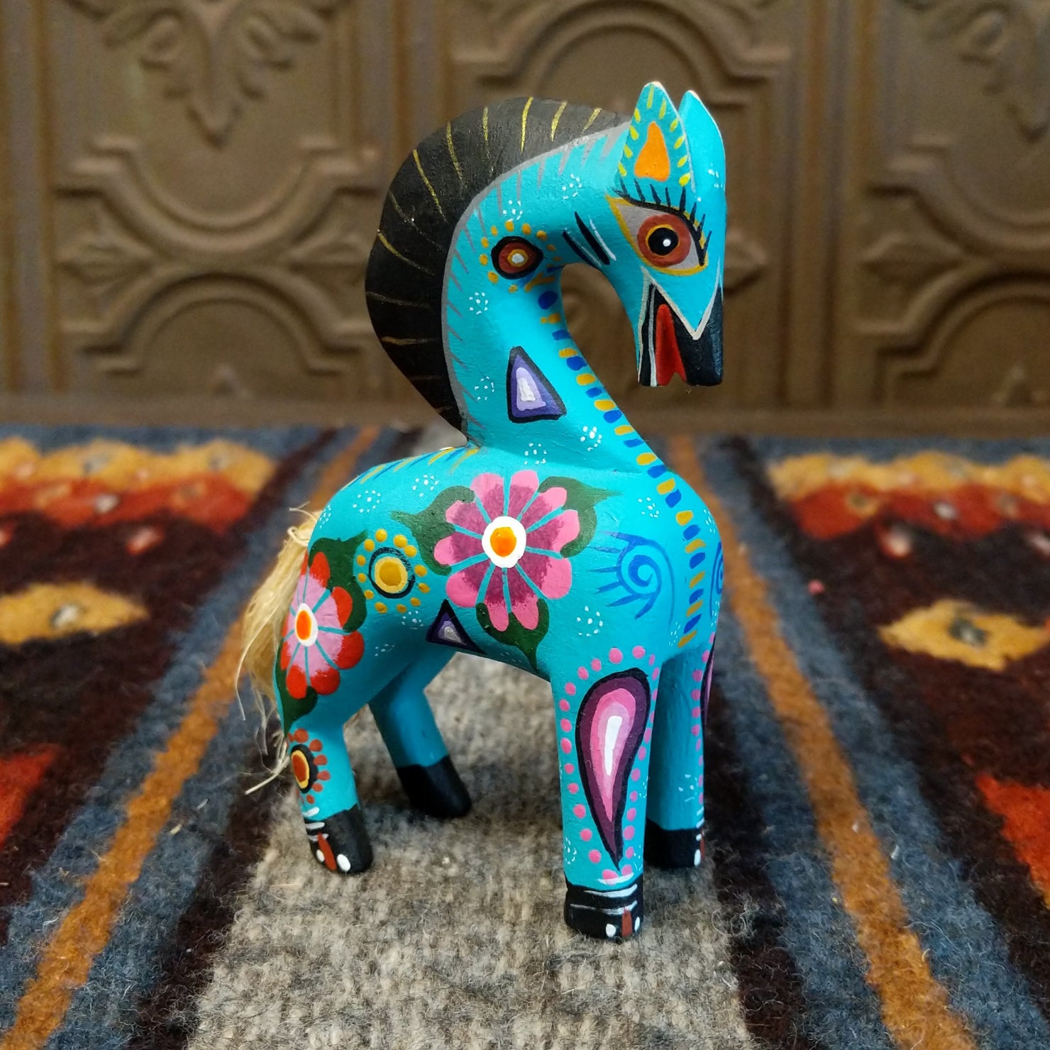 Oaxacan horse wood carving painted in vivid colors, with bold patterns on its body.