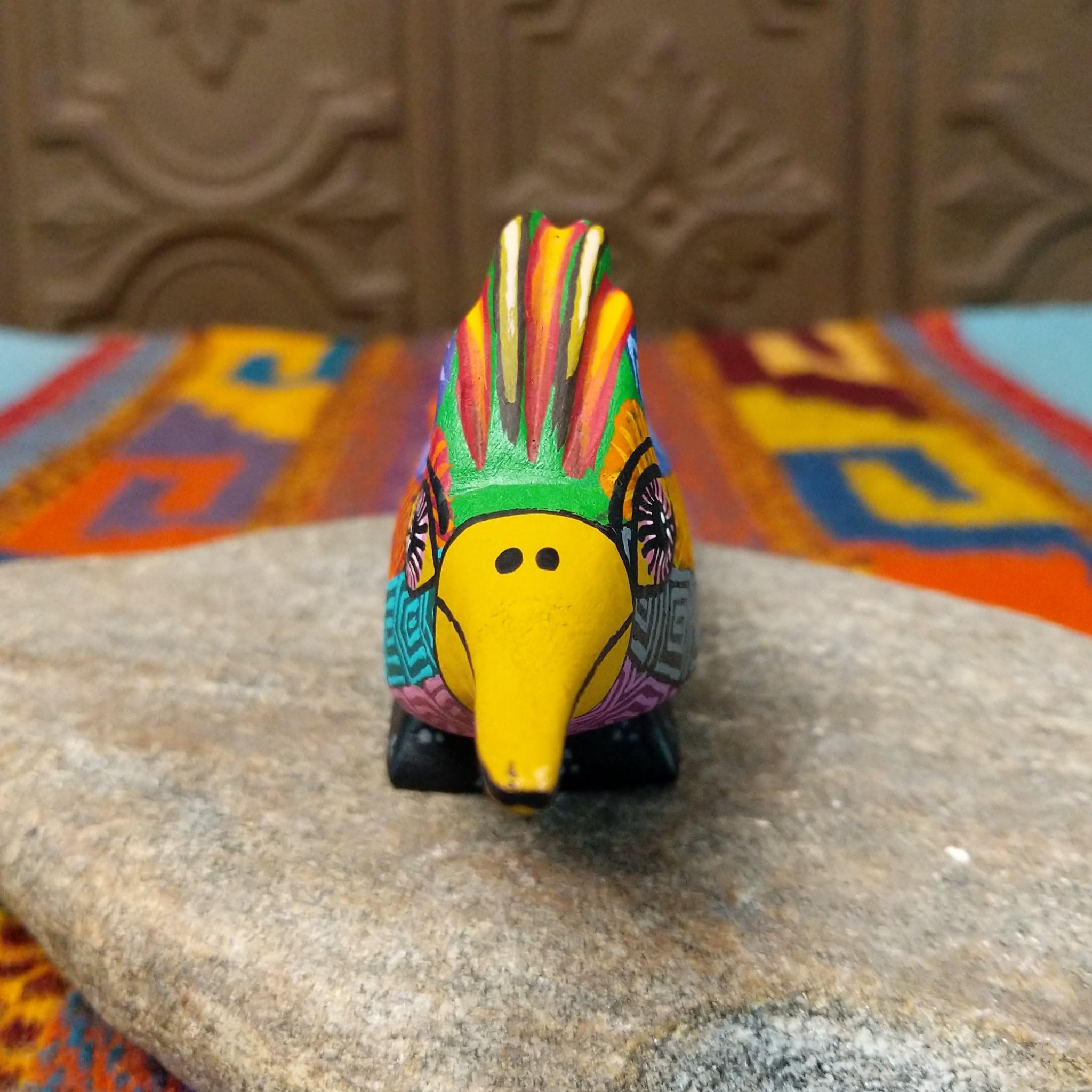 Oaxacan roadrunner wood carving by Julia Calvo Olivera with a long yellow beak, swept-back crest, and multicolored geometric patterns.