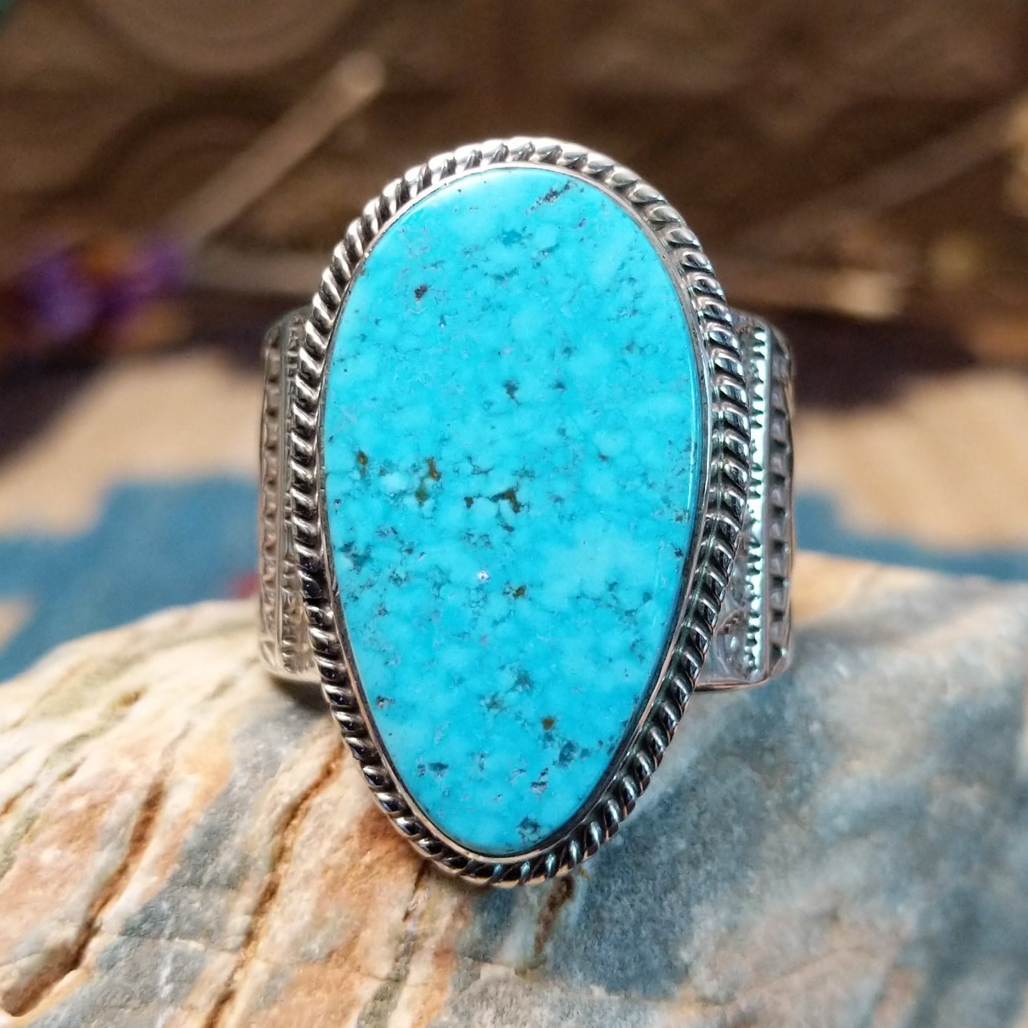 Sterling silver ring with turquoise set in an oblong bezel, framed by incised lining and stamping.