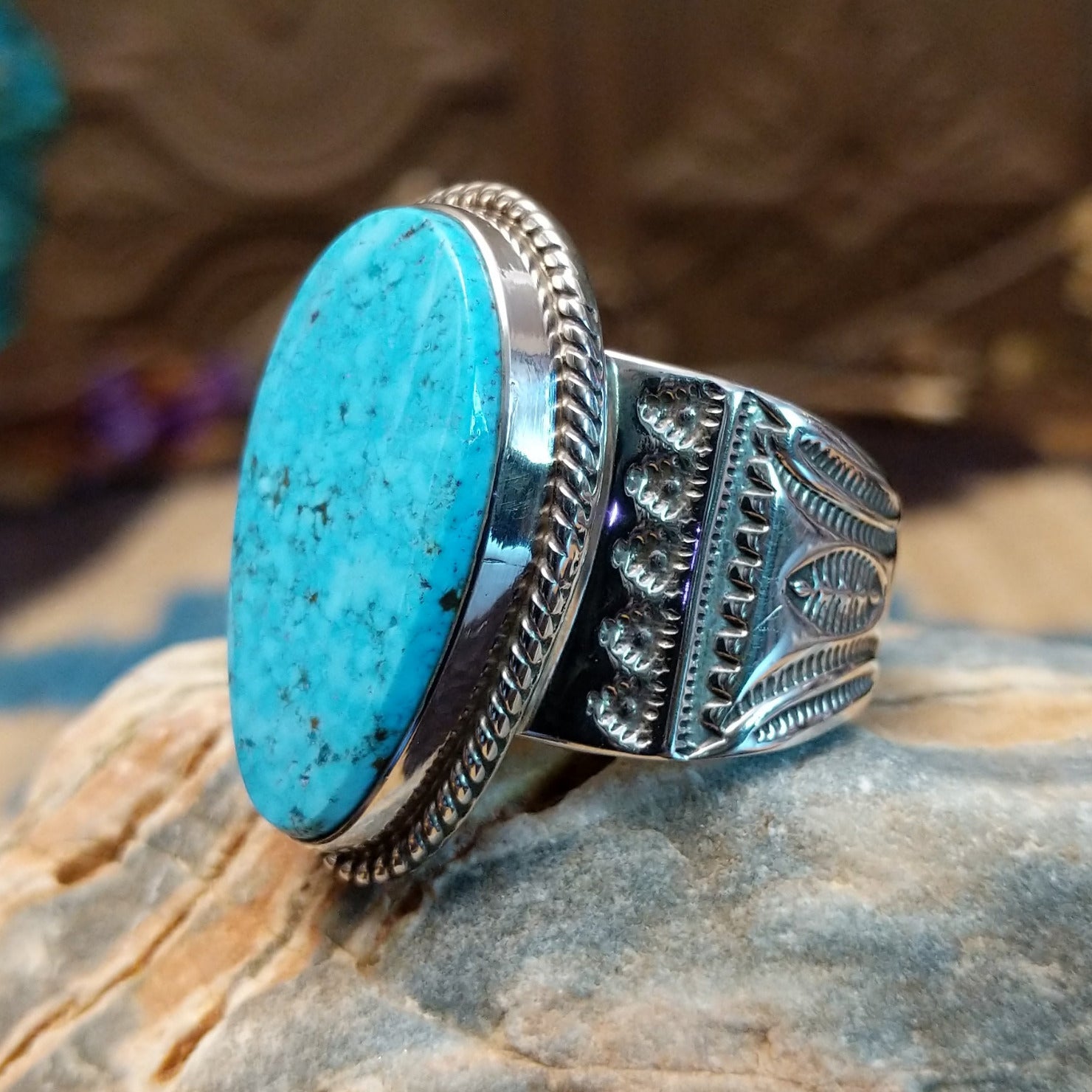 Sterling silver ring with turquoise set in an oblong bezel, framed by incised lining and stamping.