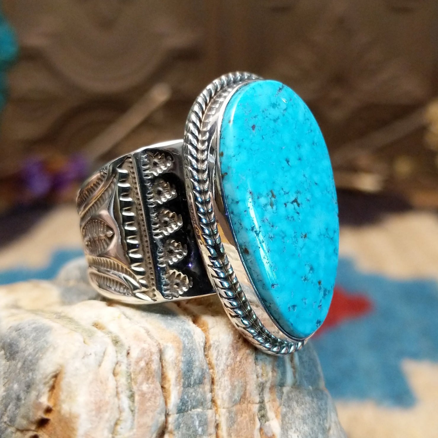 Sterling silver ring with turquoise set in an oblong bezel, framed by incised lining and stamping.