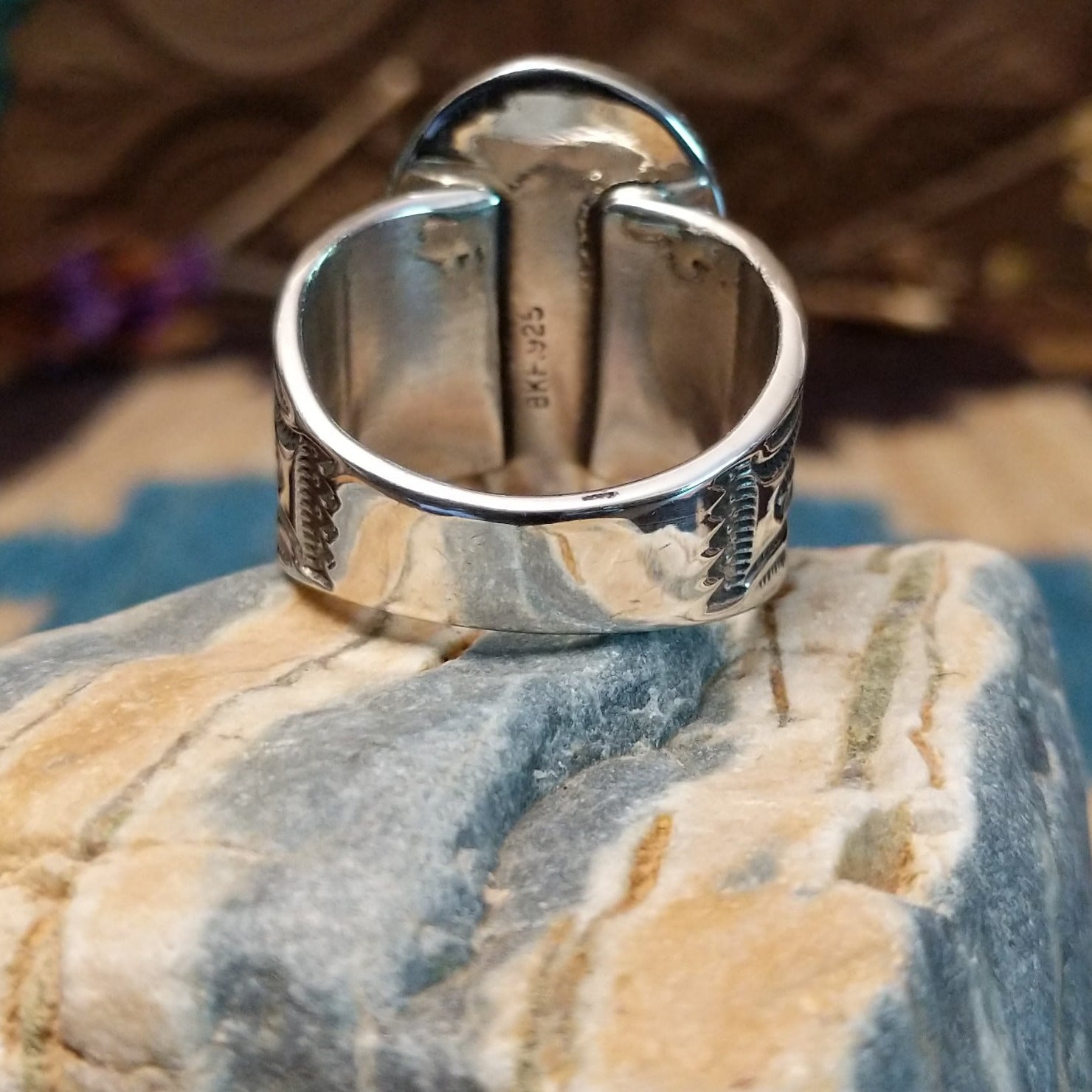 Sterling silver ring with turquoise set in an oblong bezel, framed by incised lining and stamping.