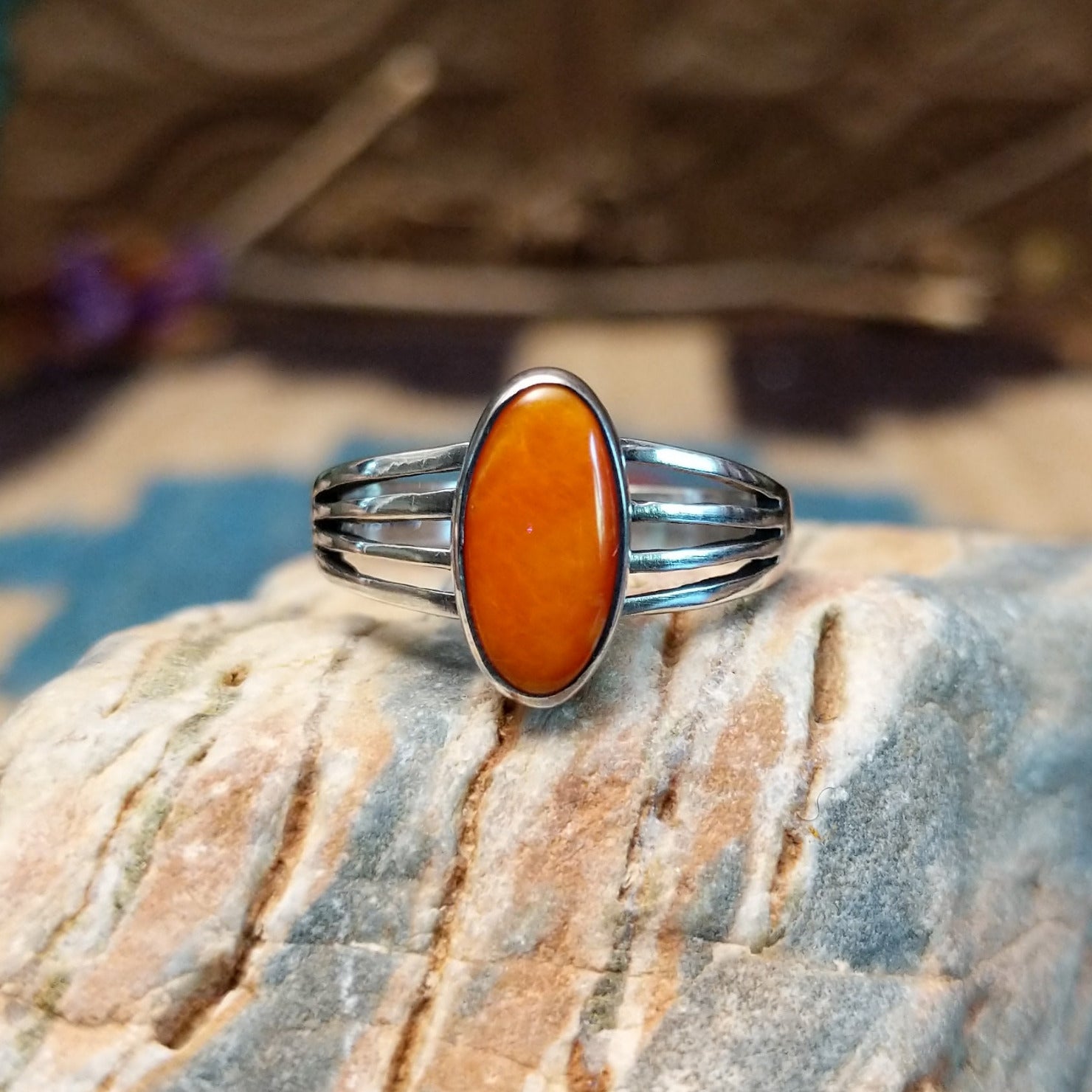 Sterling silver ring with orange spiny oyster shell set in an oval bezel and layered band.