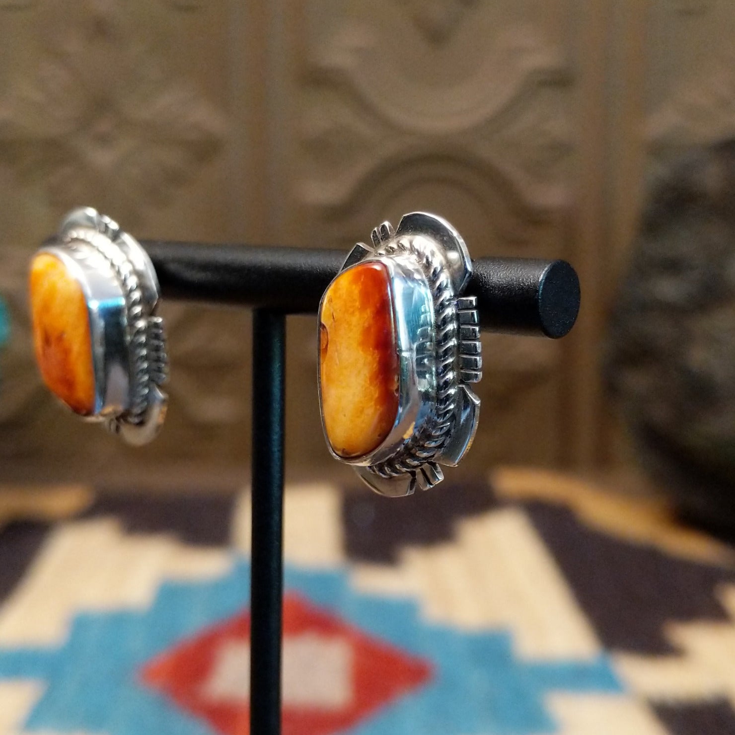 Sterling silver earrings featuring orange spiny oyster shell set in bezels, framed by twisted rope and etched setting.