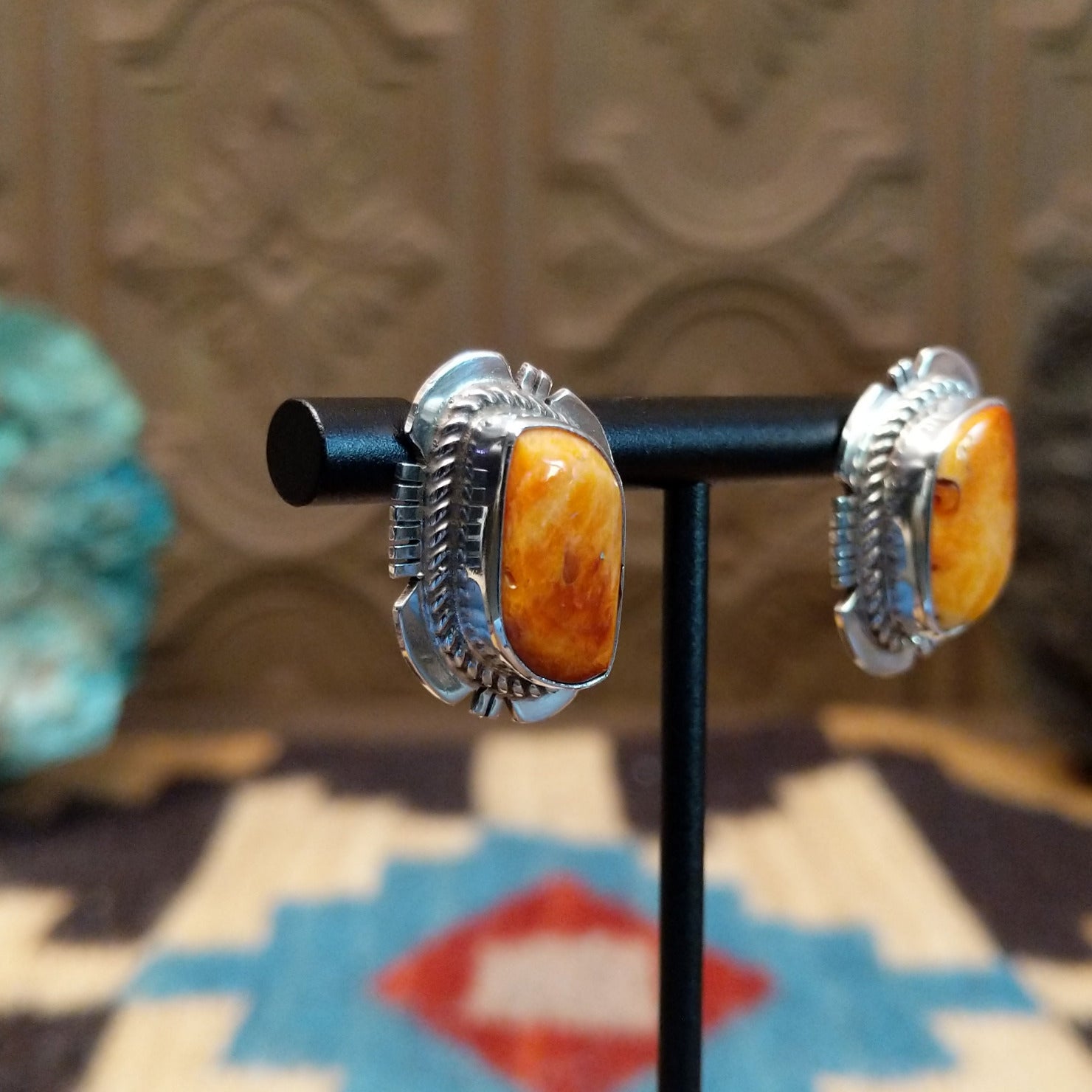 Sterling silver earrings featuring orange spiny oyster shell set in bezels, framed by twisted rope and etched setting.