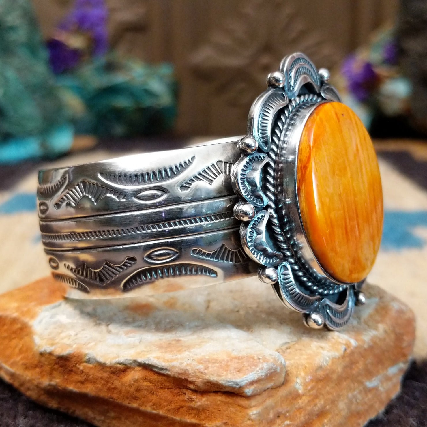 Orange spiny oyster shell portrait cuff by Philbert Secatero and Raymond Coriz, featuring a detailed shell portrait set in handcrafted Southwestern-inspired metalwork. Side view.