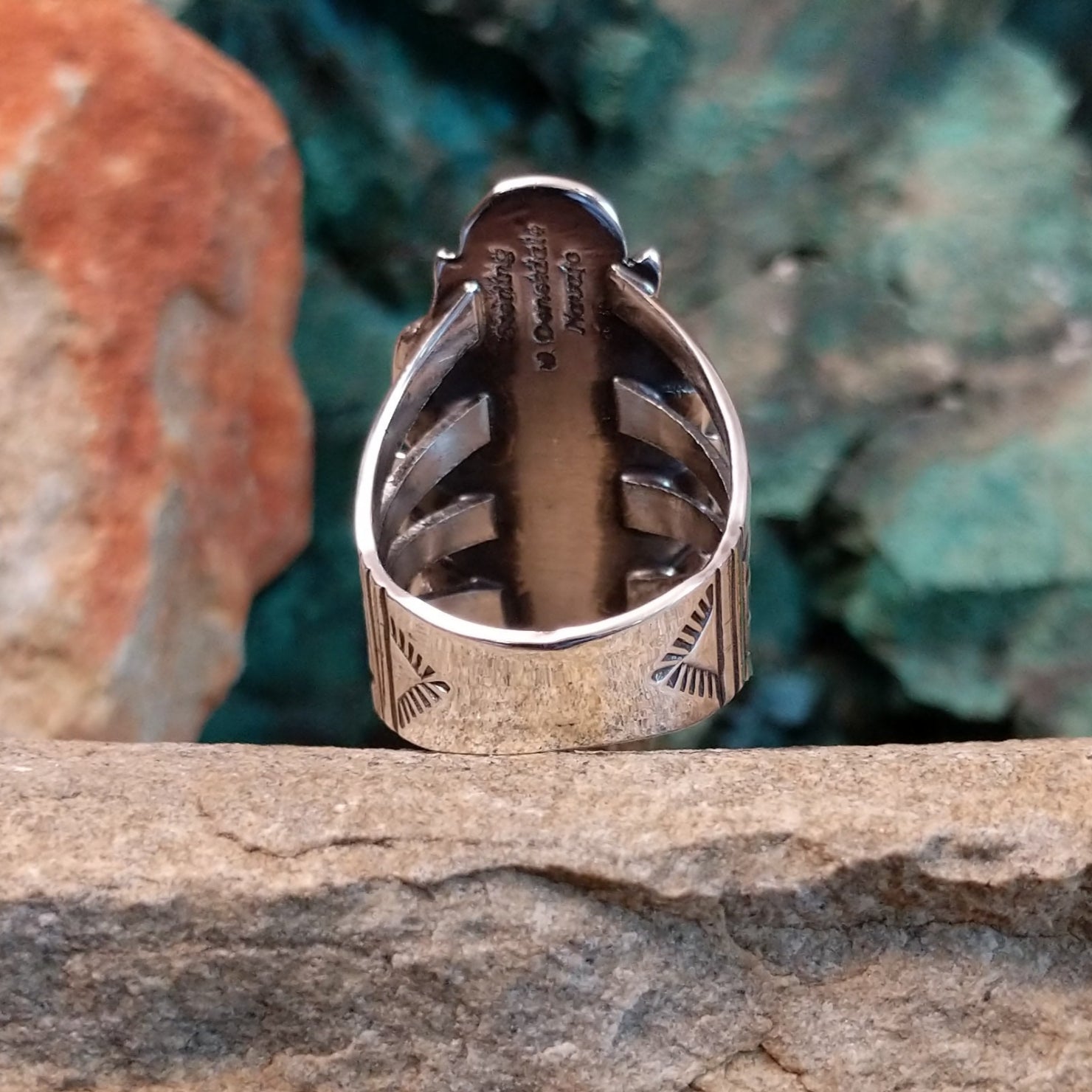 The rear of the ring reveals a polished sterling silver band etched with designs.