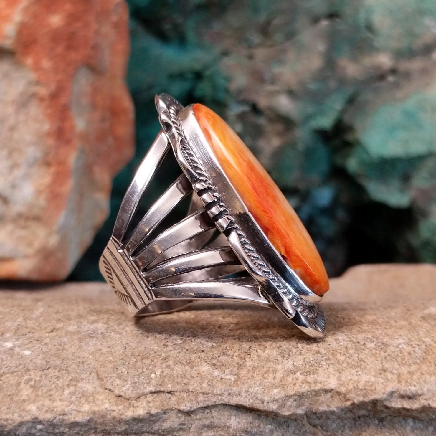 The side of the ring shows the smooth bezel with the orange spiny oyster shell, accented by twisted silver rope along the band.