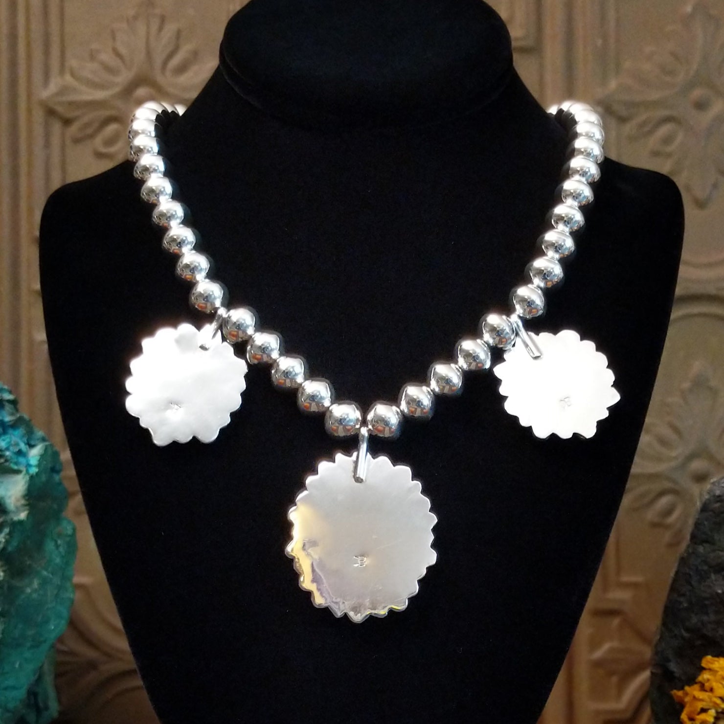 The stamped signature is on the sterling silver of the necklace pendants.