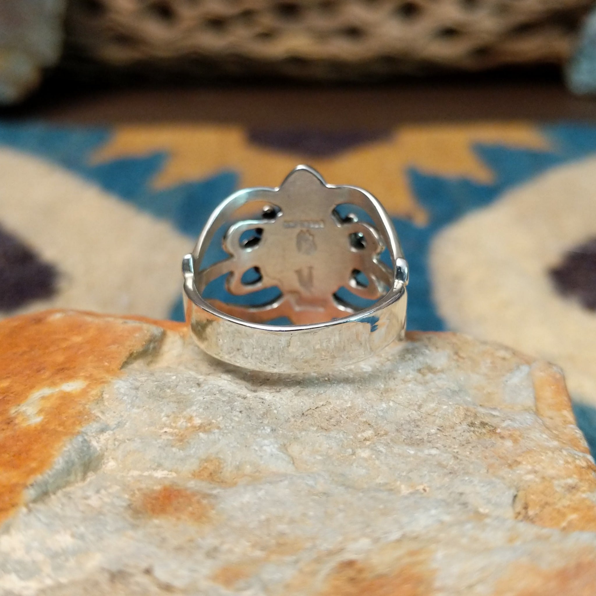 Handcrafted Navajo sterling silver ring by Raymond Coriz featuring an oval red coral cabochon surrounded by twisted rope, silver bead accents, and an ornate openwork floral design; underside view.