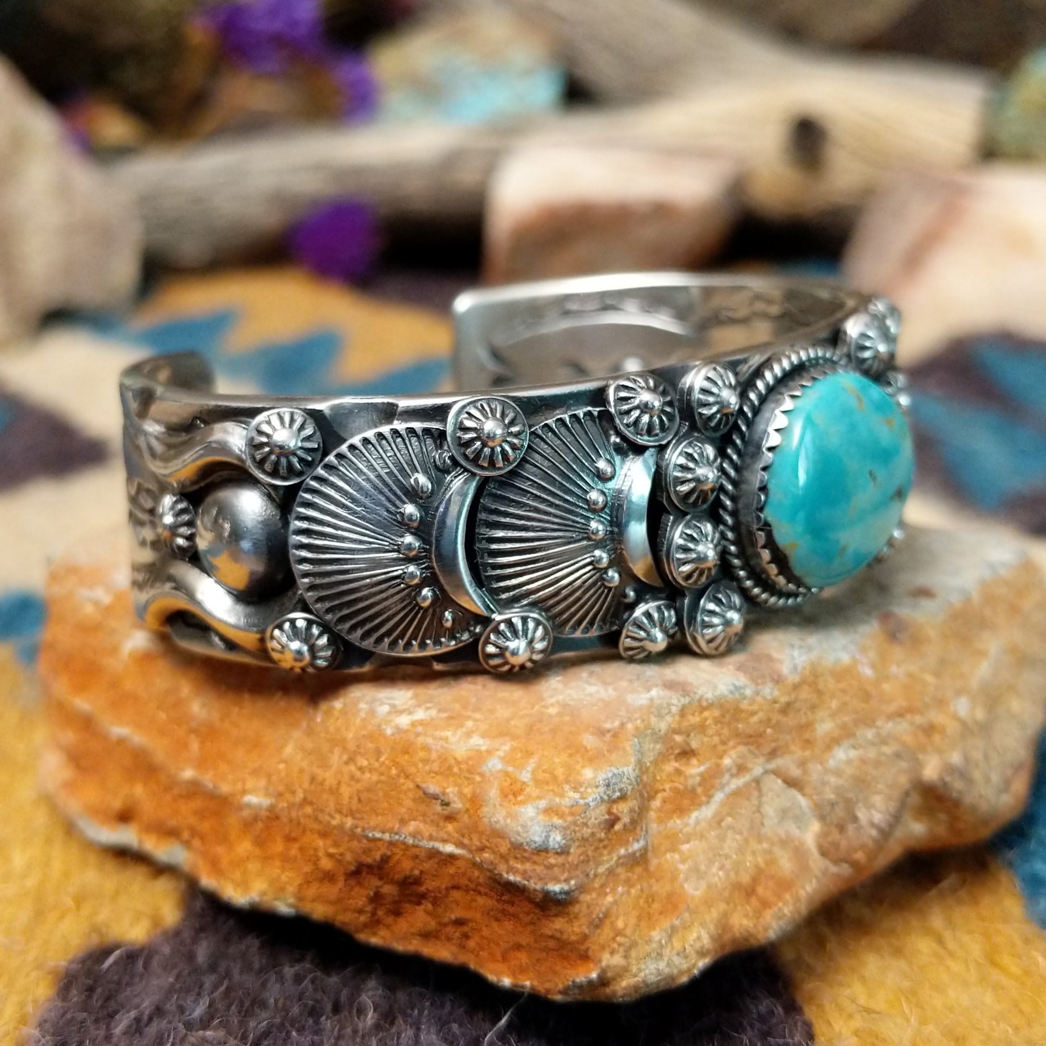 Handcrafted sterling silver cuff by Andrew Gordon featuring a Kingman turquoise cabochon with a twisted rope bezel, surrounded by ornate conchos, fan motifs, silver beadwork, and hand-stamped Southwestern details; side view.
