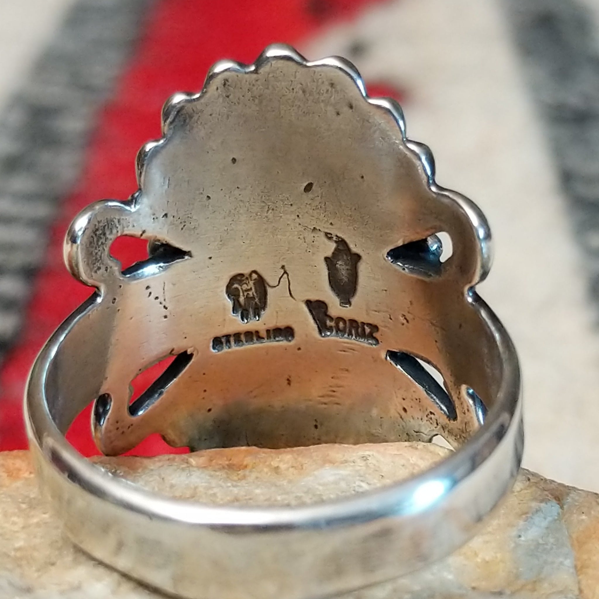 Ornate red spiny oyster shell ring by Raymond Coriz featuring an oval red-orange shell cabochon surrounded by twisted rope, fan-shaped silverwork, scrolls, and decorative silver beads; artisan and Sterling Silver stamp.