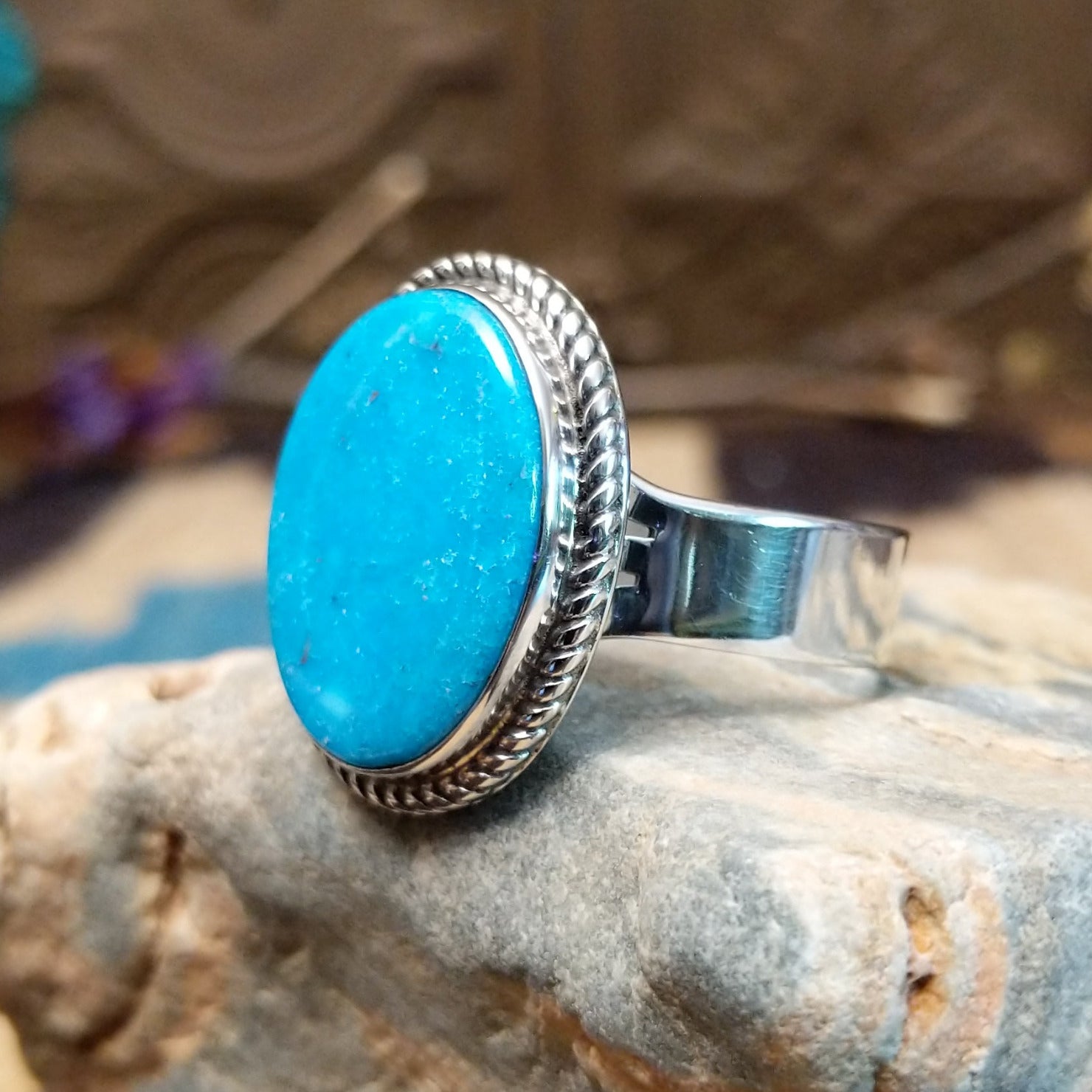 Sterling siler ring with turquoise set in the oval bezel, framed by twisted rope accents.