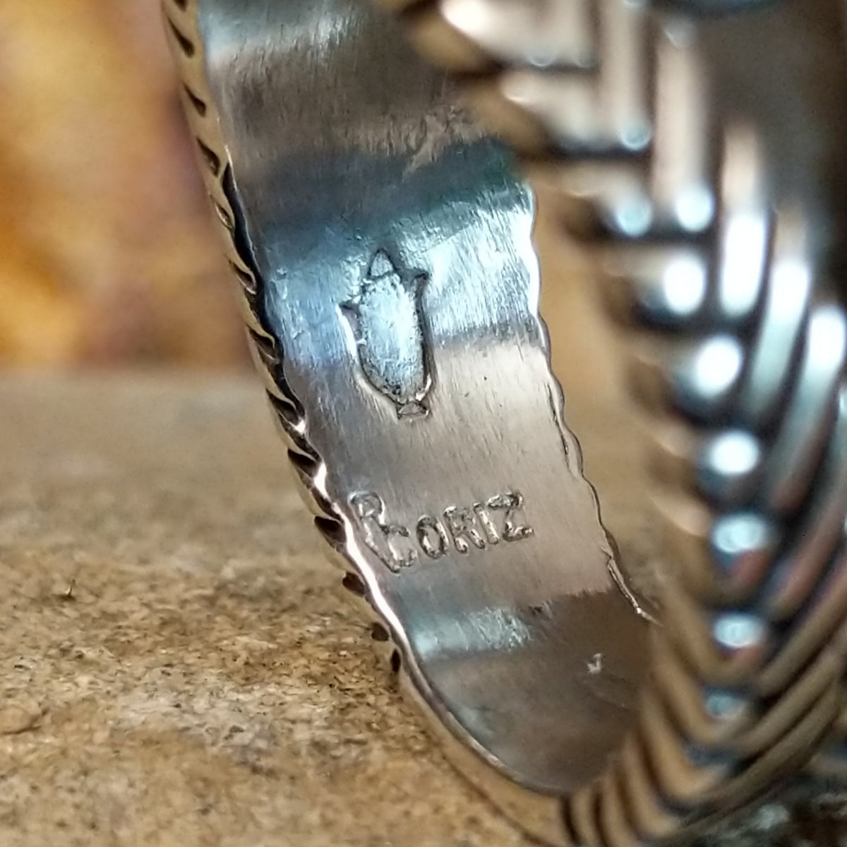 The artisan's signature is stamped on the underside of the band.