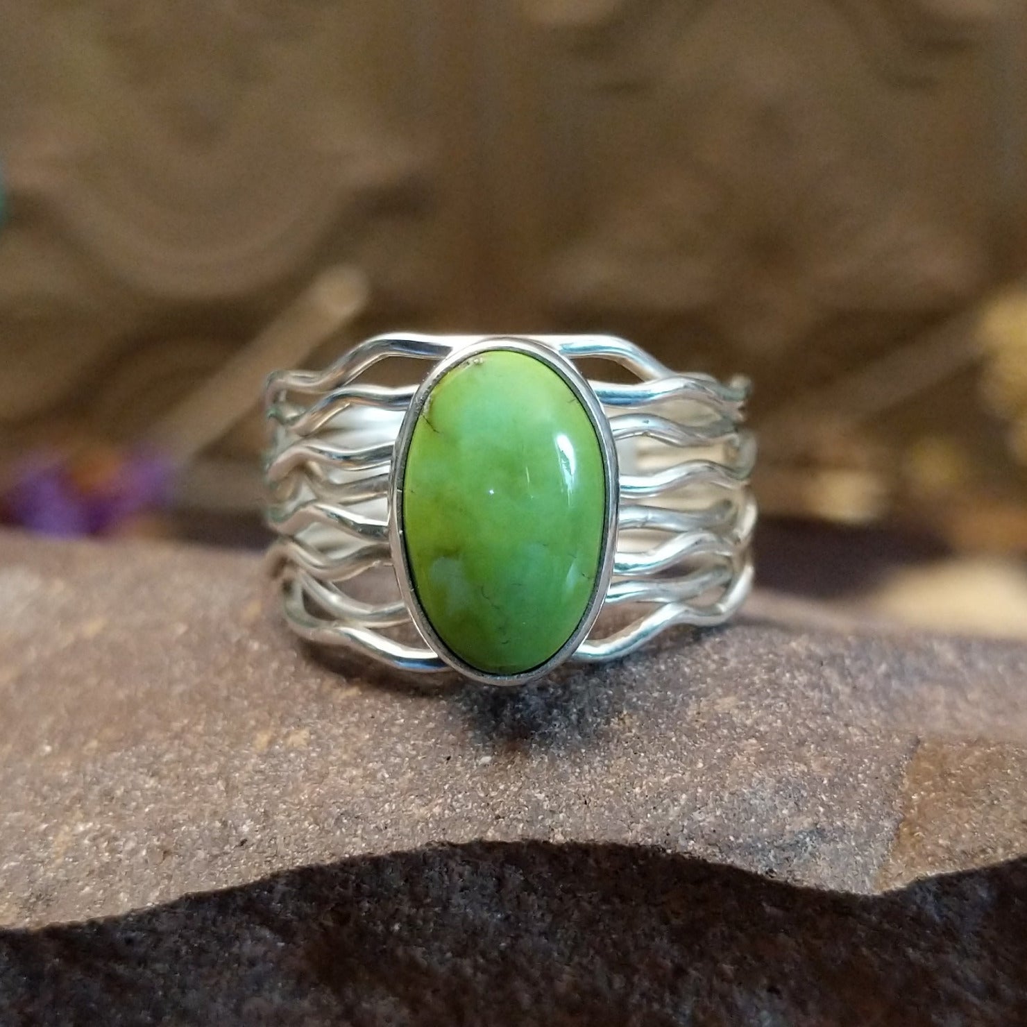 Sterling silver ring with Sonoran gold turquoise set in an oval bezel and strands of silver creating the band.