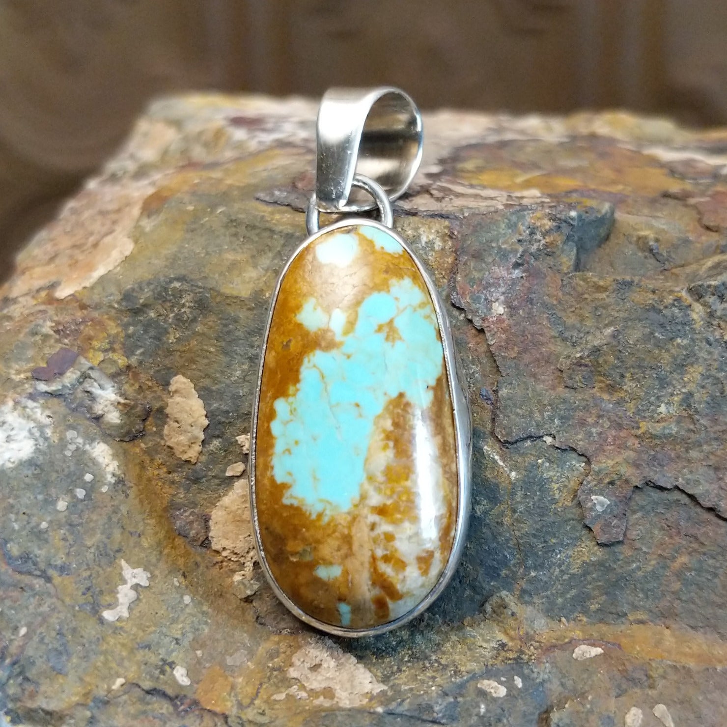 Handcrafted by Navajo artist L.P., this elliptic pendant features genuine #8 Turquoise set in sterling silver.
