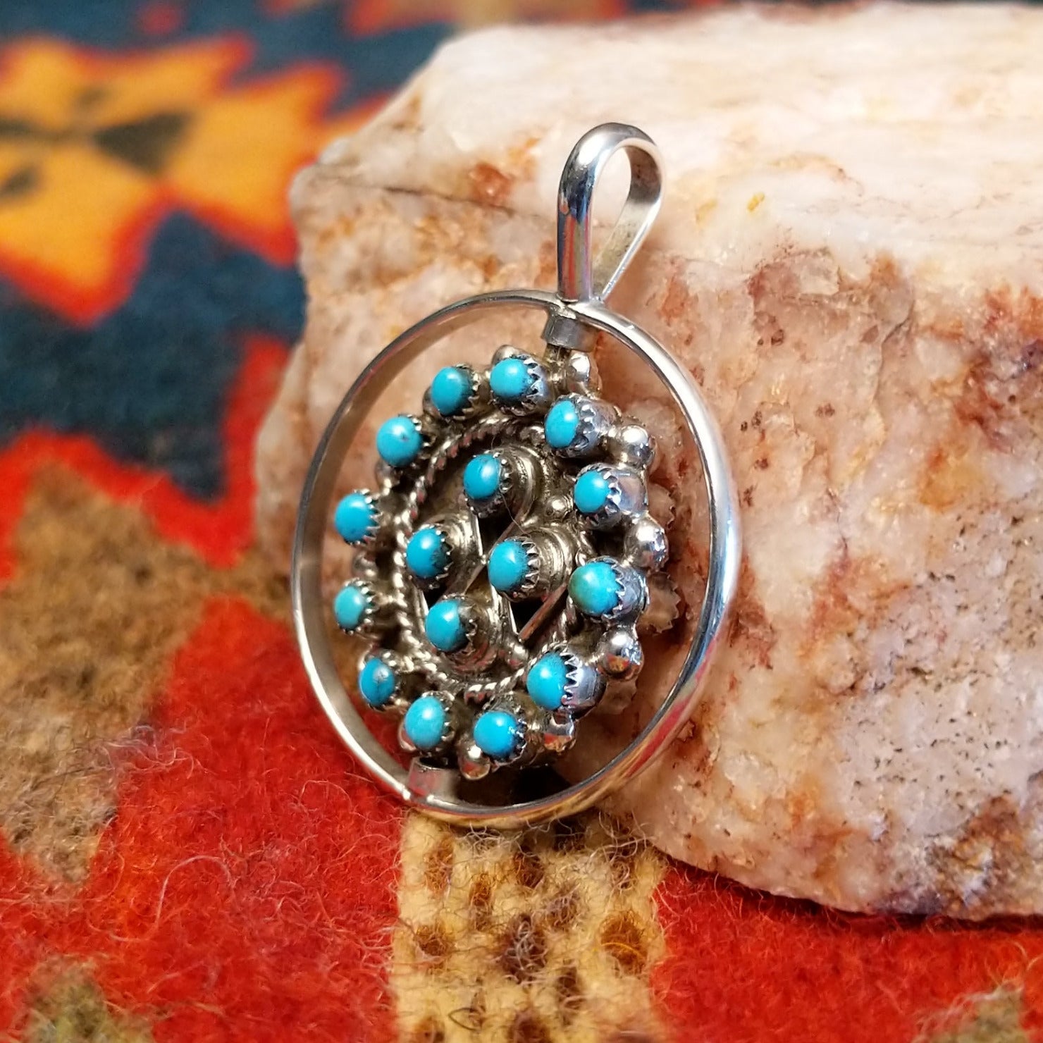 Navajo Turquoise and Coral Reversible Pendant features vibrant turquoise stones on one side, and coral on the other, set in sterling silver. Side view of turquoise side.