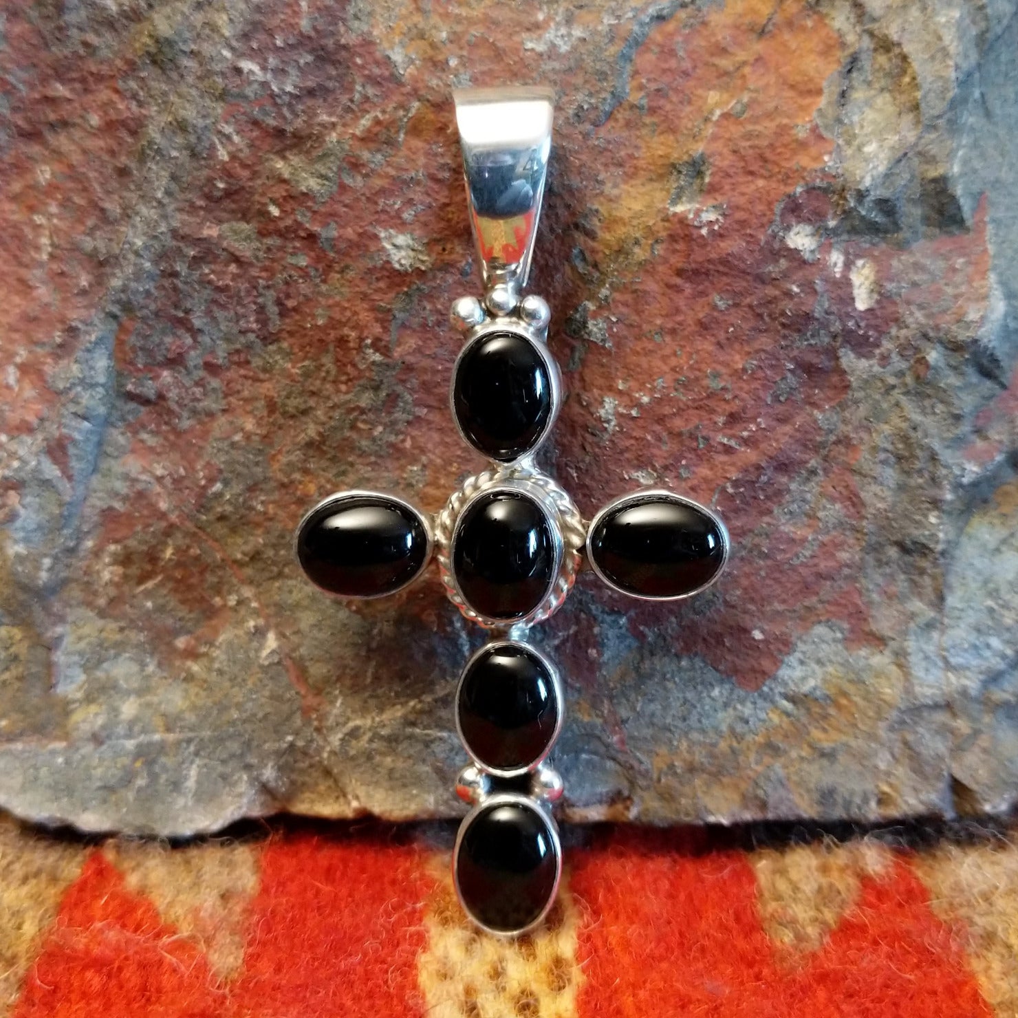 Handmade Navajo silver cross pendant featuring a black onyx stone by Ann Curley.