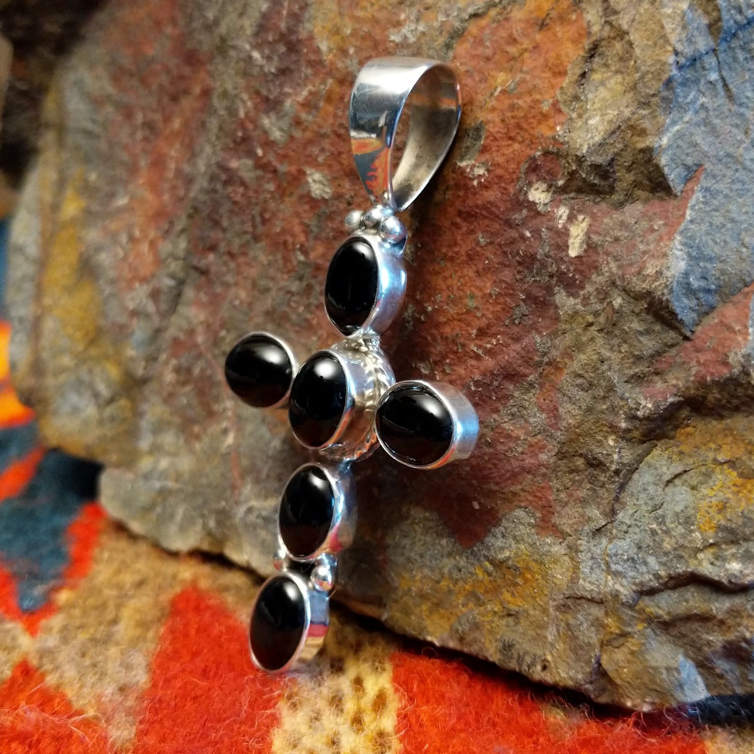 Handmade Navajo silver cross pendant featuring a black onyx stone by Ann Curley.