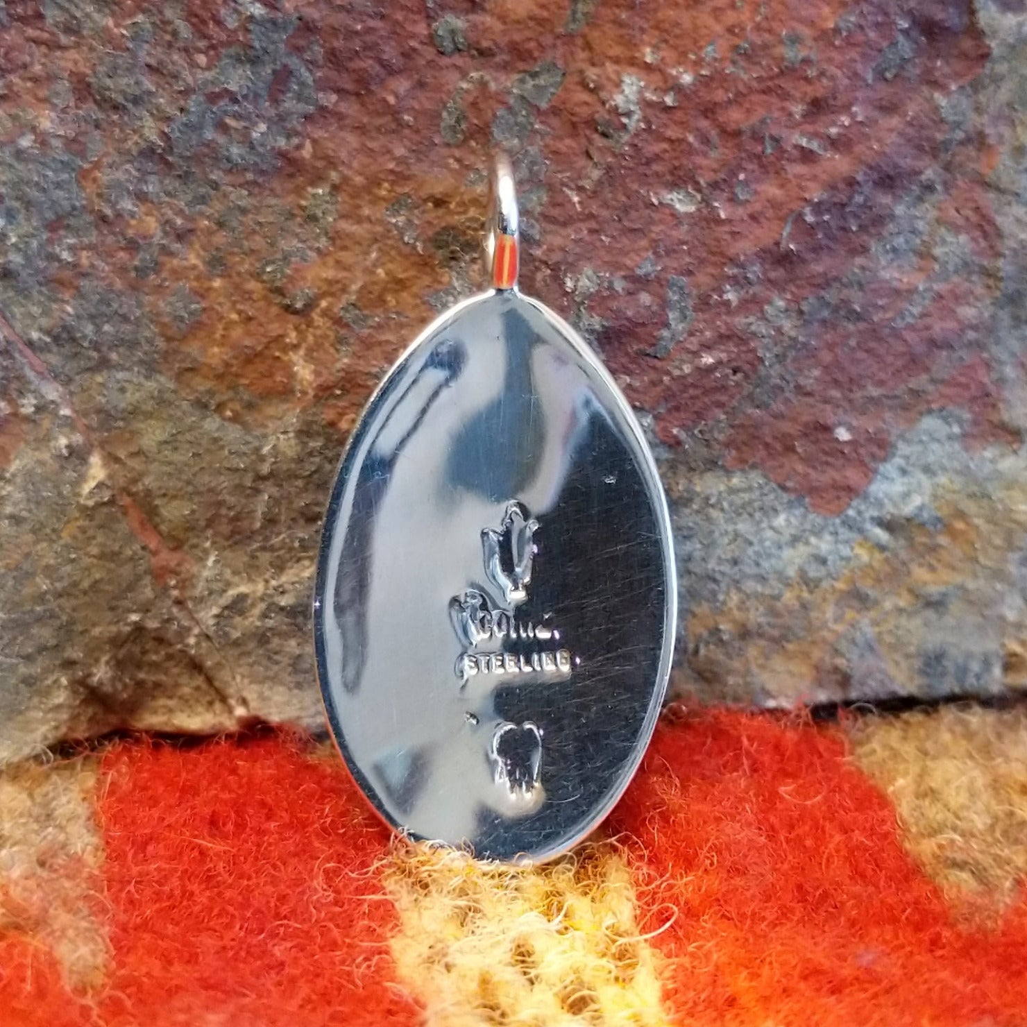 Oval sterling silver pendant with central cross by Navajo artisan Raymond Coriz showing artisan hallmark