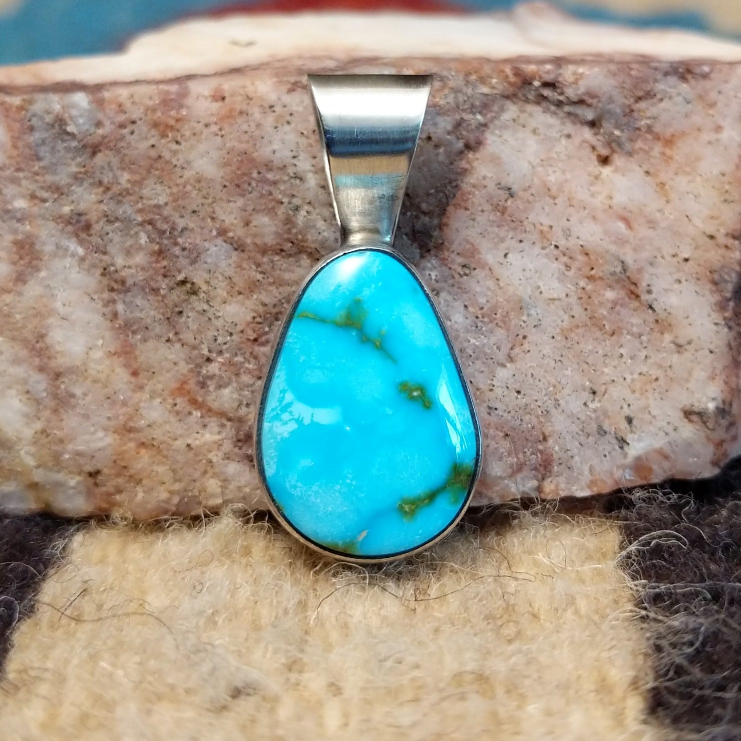 Ovoid sterling silver pendant featuring a polished Sonoran Gold turquoise stone with blue-green color and golden matrix, handcrafted by Native American artist Fred Guerro Jr. Front View