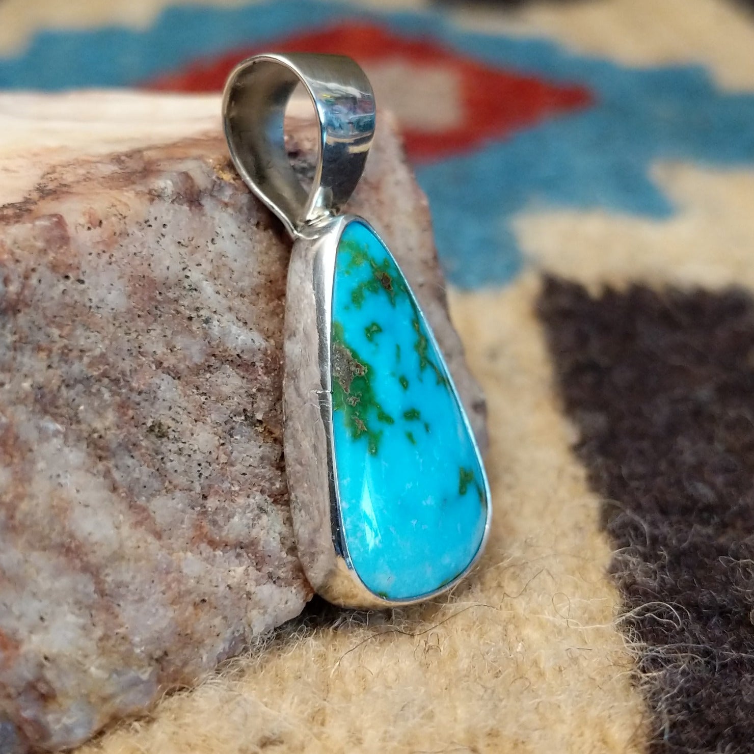 Teardrop sterling silver pendant featuring a polished Sonoran Gold turquoise stone with vivid blue-green color and natural golden matrix, handcrafted by Bernyse Chavez. Side view.