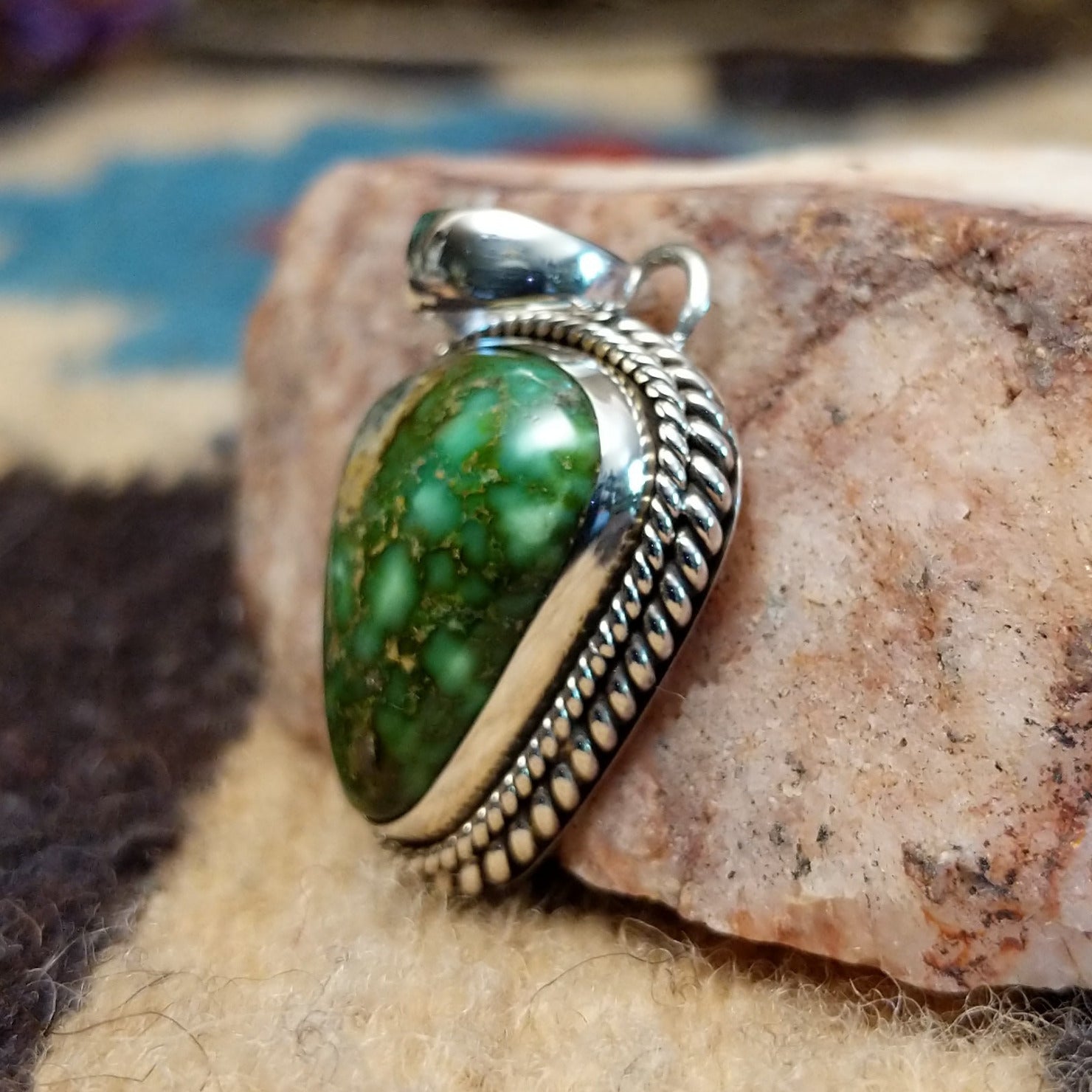 Triangular sterling silver pendant featuring a polished Sonoran Gold turquoise stone with blue-green tones and natural golden matrix, handcrafted by Navajo artist Artie Yellowhorse. Side view.