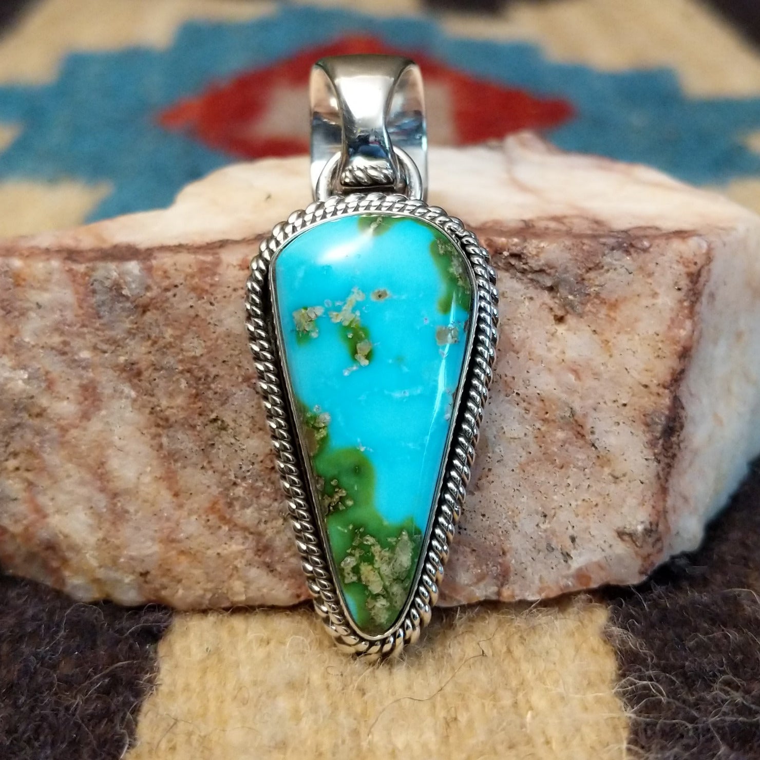 Deltoid-shaped sterling silver pendant featuring Sonoran Gold turquoise with vivid blue-green tones and natural golden matrix, handcrafted by Navajo artist Artie Yellowhorse. Front view.