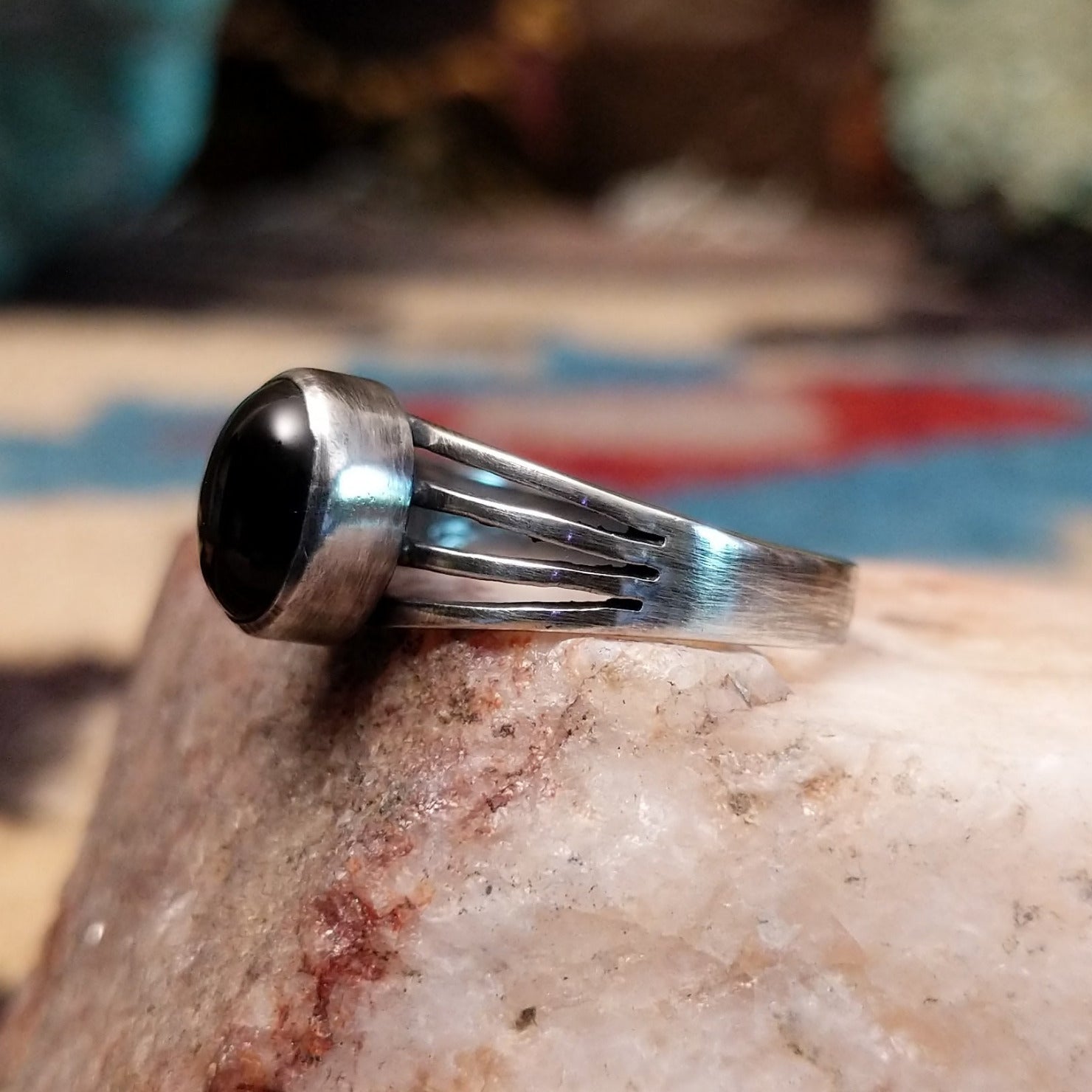 Sterling silver split-band ring by Raymond Coriz featuring a polished black onyx stone in a sleek Southwestern design. Side view.