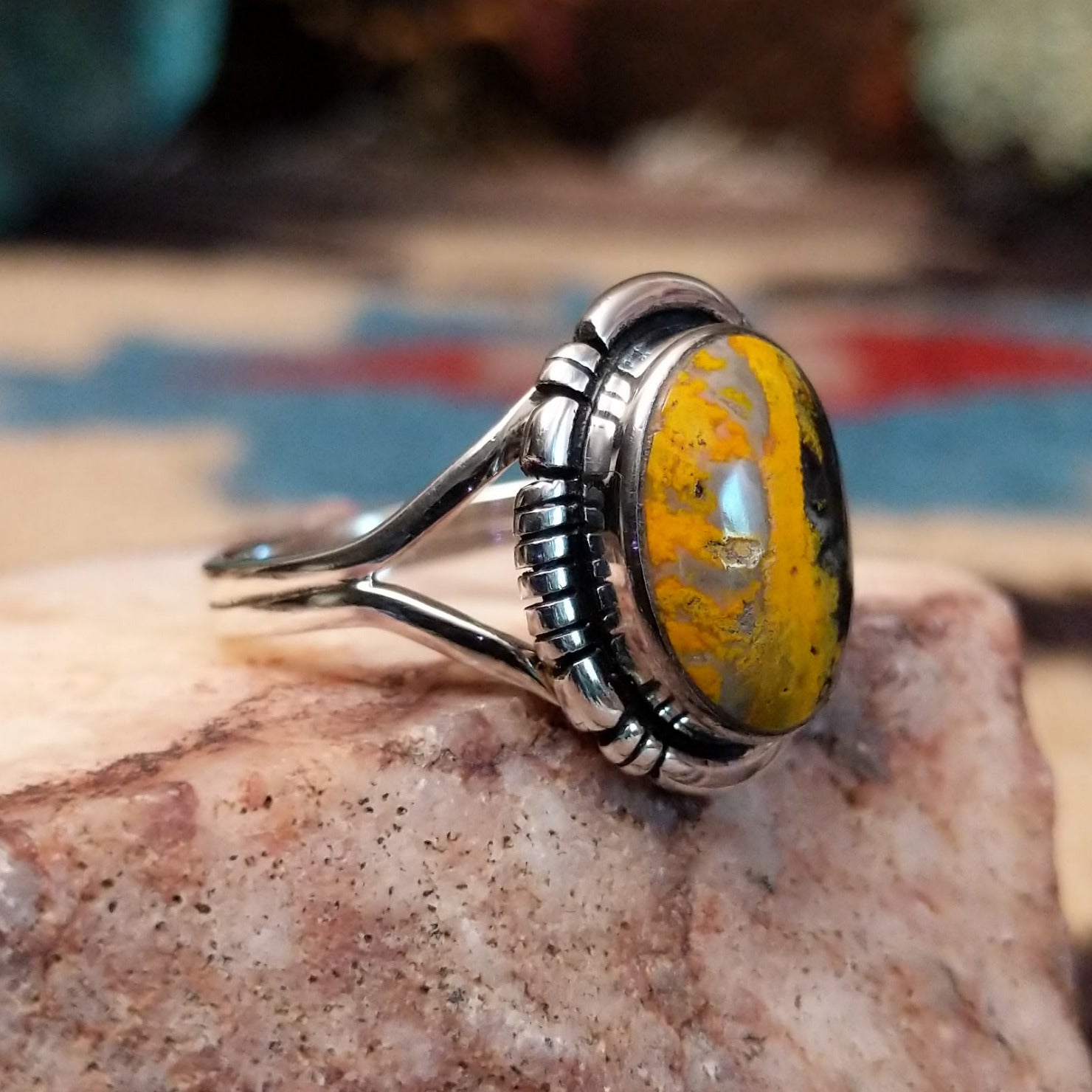 Navajo sterling silver ring with an oval Bumblebee Jasper stone featuring bold yellow, orange, black, and cream natural patterns. Side view.