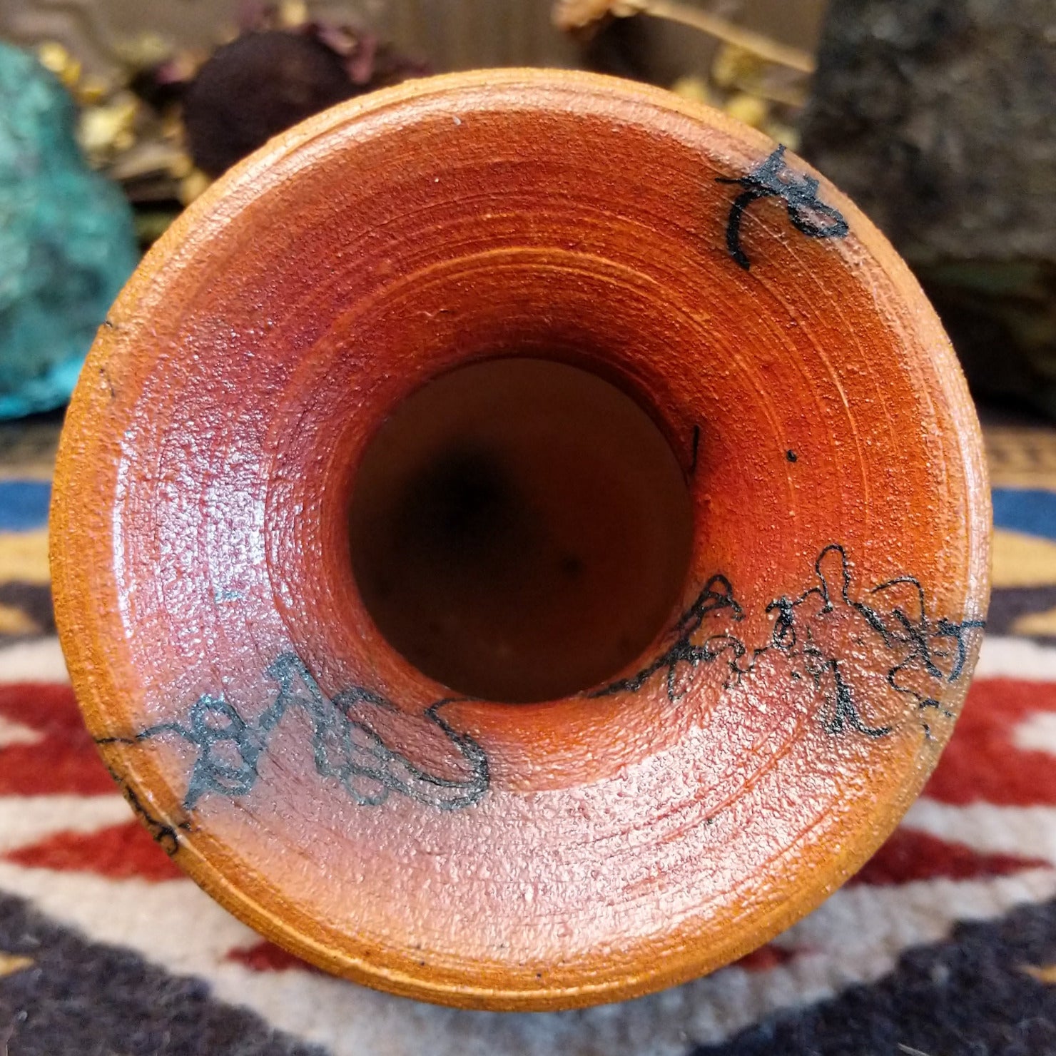 Small handcrafted terracotta horsehair vase with a rounded body and flared rim, decorated with black abstract horsehair firing patterns by artisan Jim Calhoun. Top view.