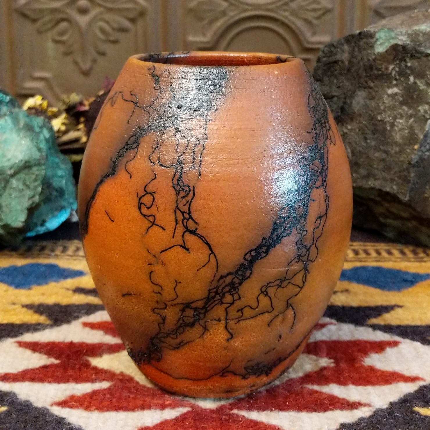Small oval terracotta horsehair vase handcrafted by local artisan Jim Calhoun, featuring warm earthy clay tones and delicate black horsehair fire patterns on a smooth rounded surface.