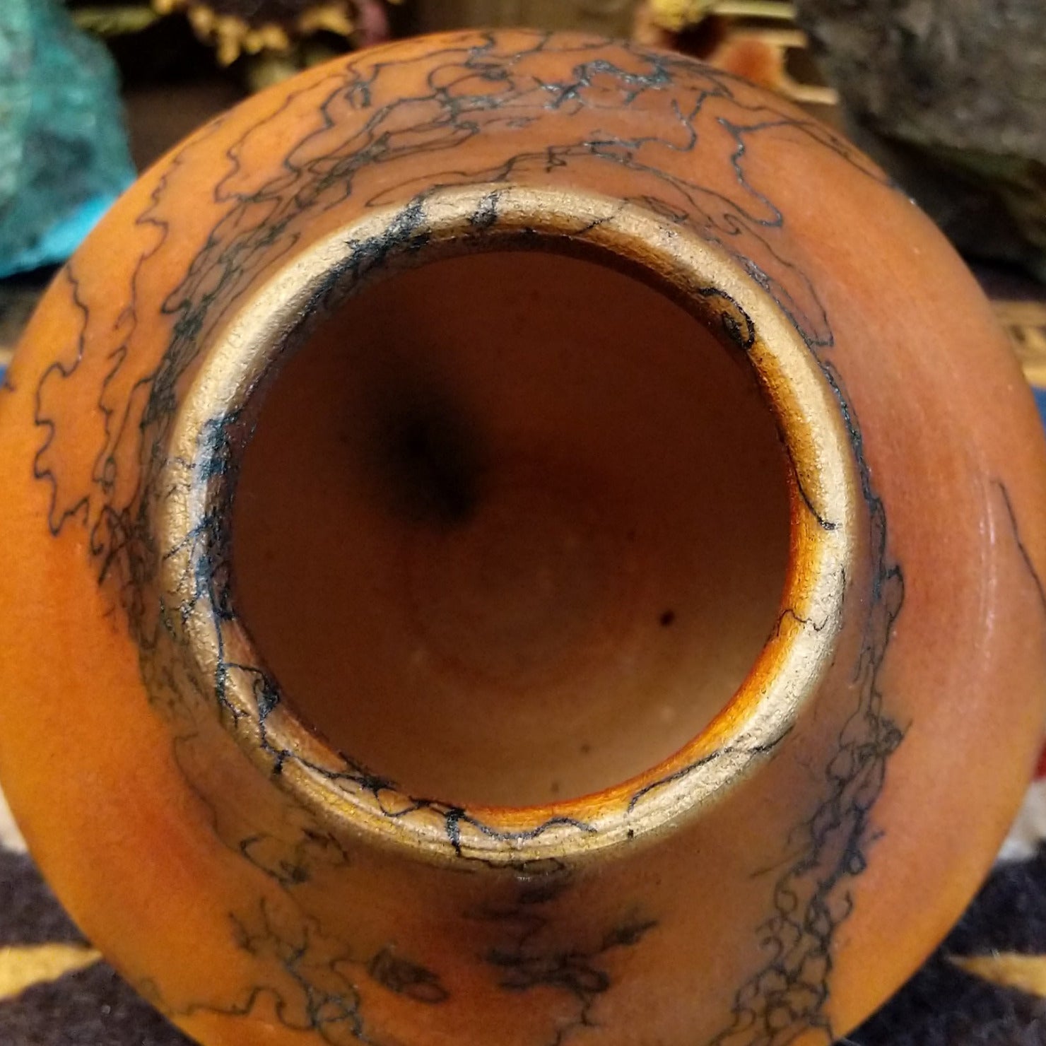 Small terracotta horsehair pot handcrafted by local artisan Jim Calhoun, featuring earthy clay tones and unique black horsehair fire patterns on a rounded pottery form. Top view.