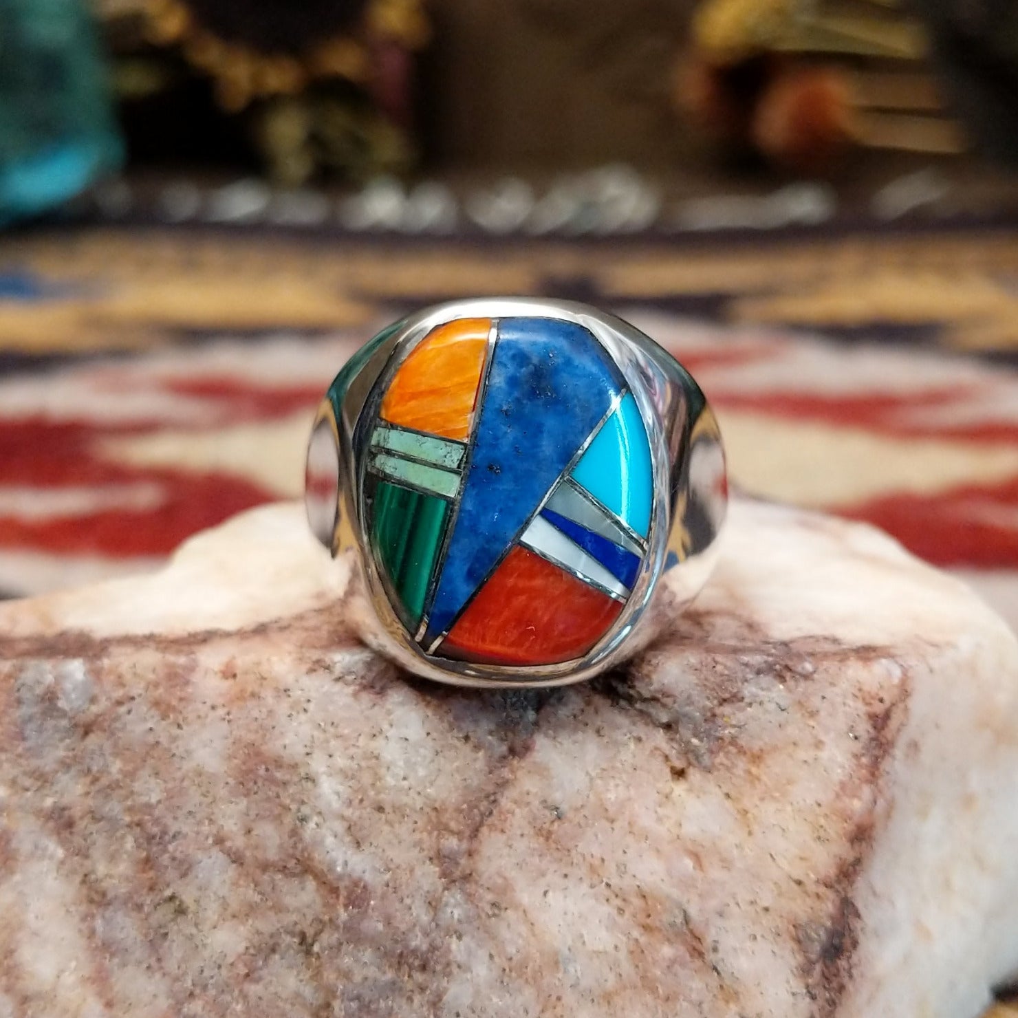 Handcrafted sterling silver multistone inlay ring by Navajo artist Bernadine Joe featuring Denim Lapis, Lapis, red and orange Spiny Oyster Shell, Mother of Pearl, Turquoise, and Malachite arranged in a colorful geometric mosaic design.