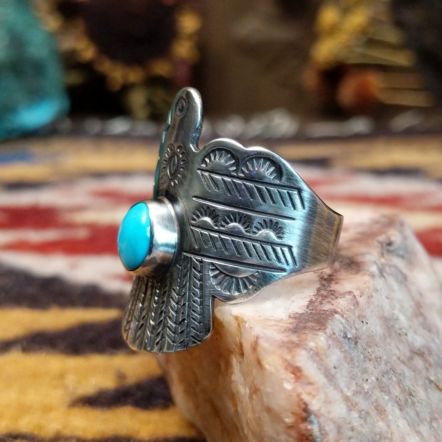 Handcrafted sterling silver Thunderbird ring by Raymond Coriz featuring a turquoise stone and traditional Southwestern Native American design details. Side view.