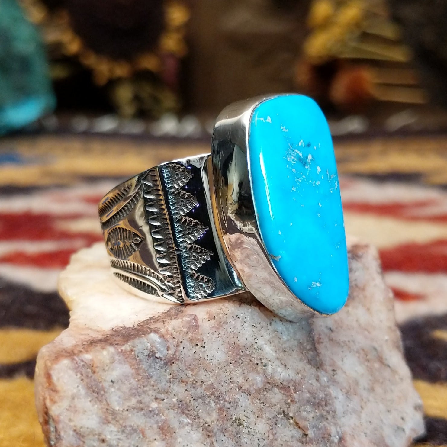 Handcrafted Navajo sterling silver ring by L.J. featuring a turquoise stone with traditional stamped silver detailing in a Southwestern design. Side view.