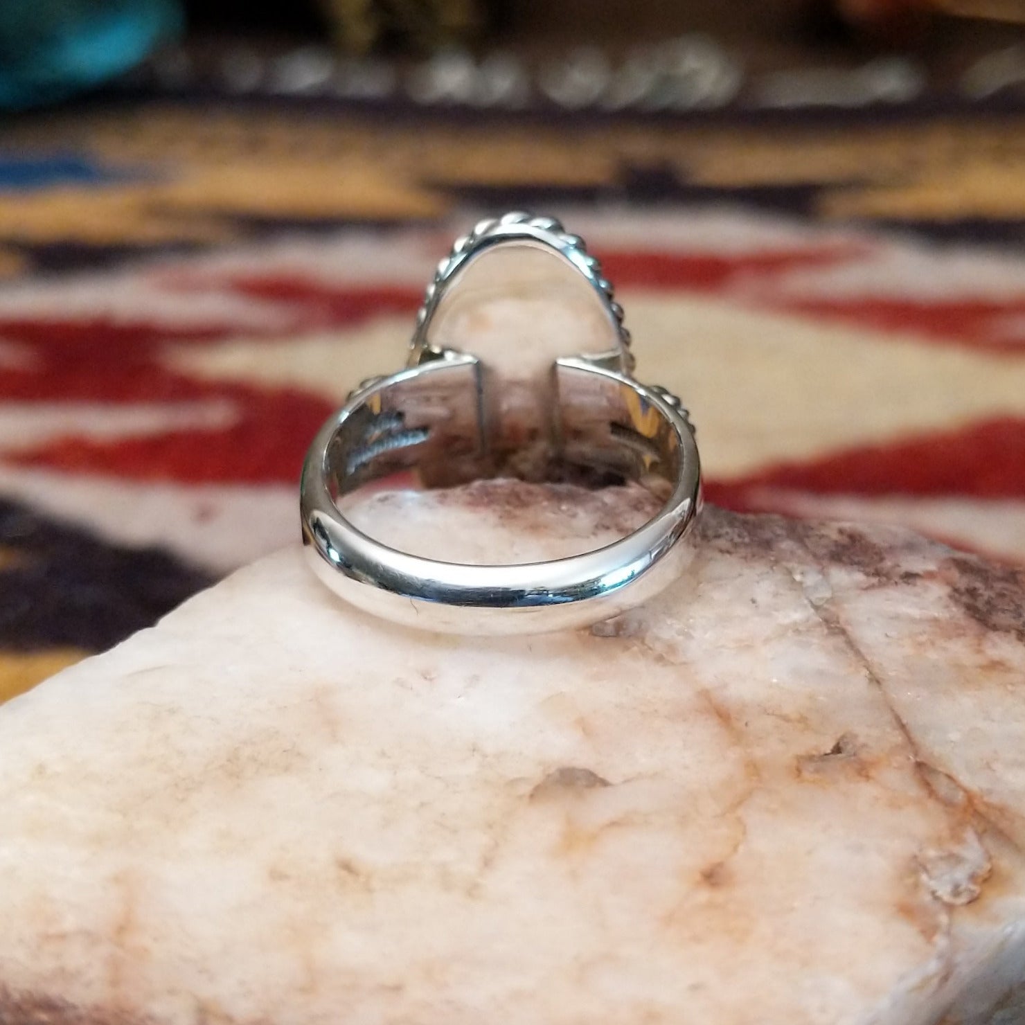 Handcrafted sterling silver ovoid ring by Artie Yellowhorse featuring a deep purple sugilite stone in a polished Southwestern Native American design. Underside view.