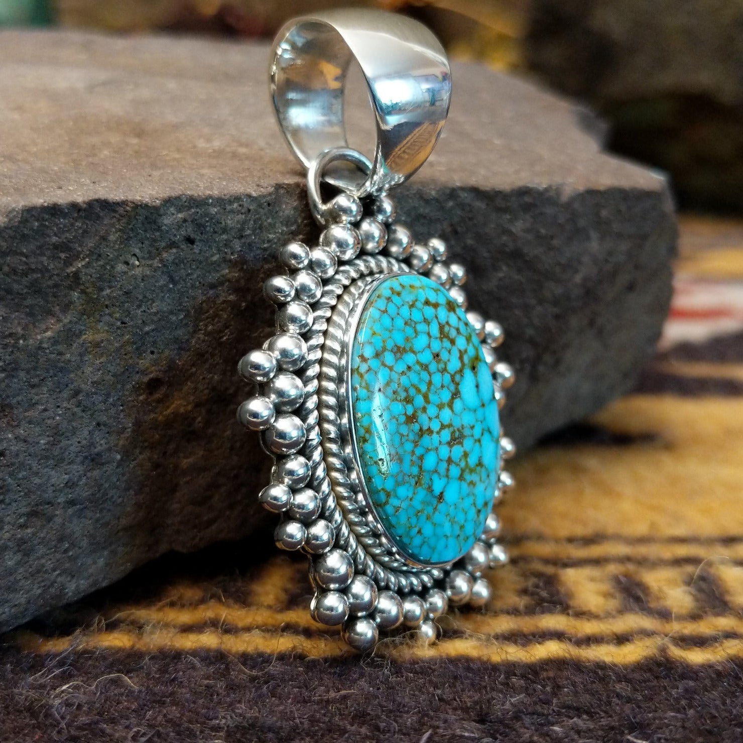Handcrafted sterling silver pendant by Artie Yellowhorse featuring a Kingman turquoise stone in a polished Southwestern Native American design. Side view.