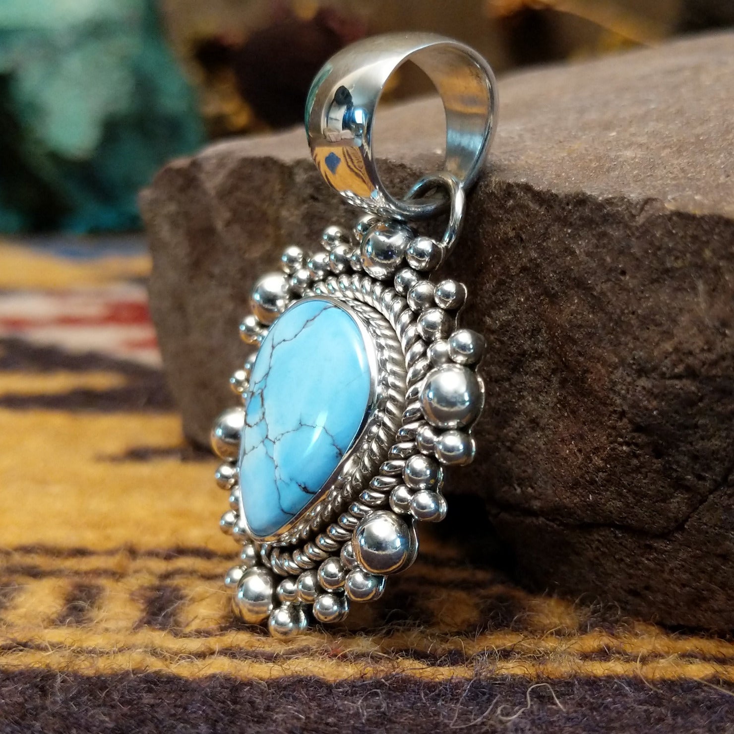 Handcrafted sterling silver pendant by Artie Yellowhorse featuring a Golden Hills turquoise stone in a polished Southwestern Native American design. Side view.