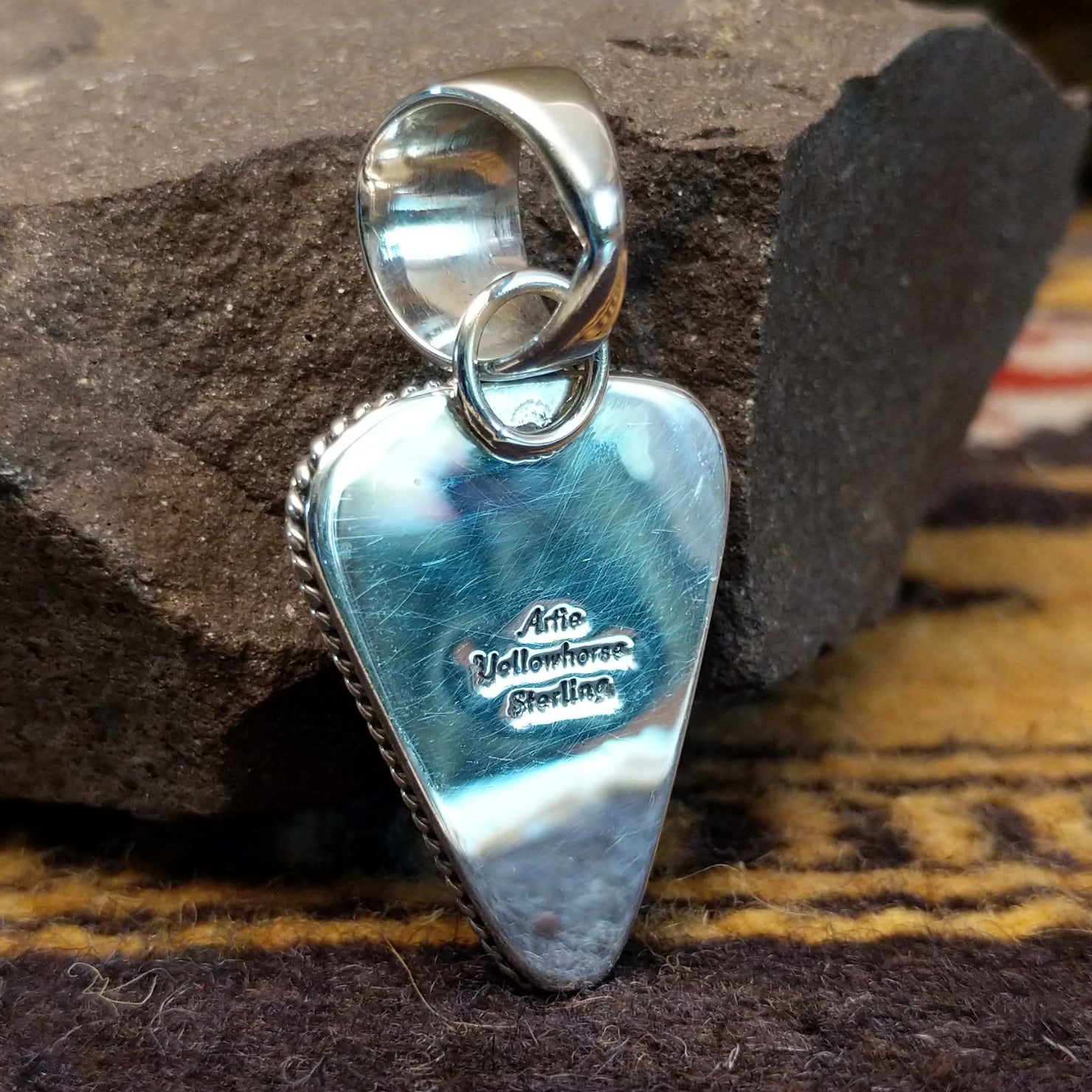 Handcrafted sterling silver pendant by Artie Yellowhorse featuring a purple spiny oyster shell in a triangular Southwestern Native American design. Back view showcasing artisan and Sterling Silver stamp.