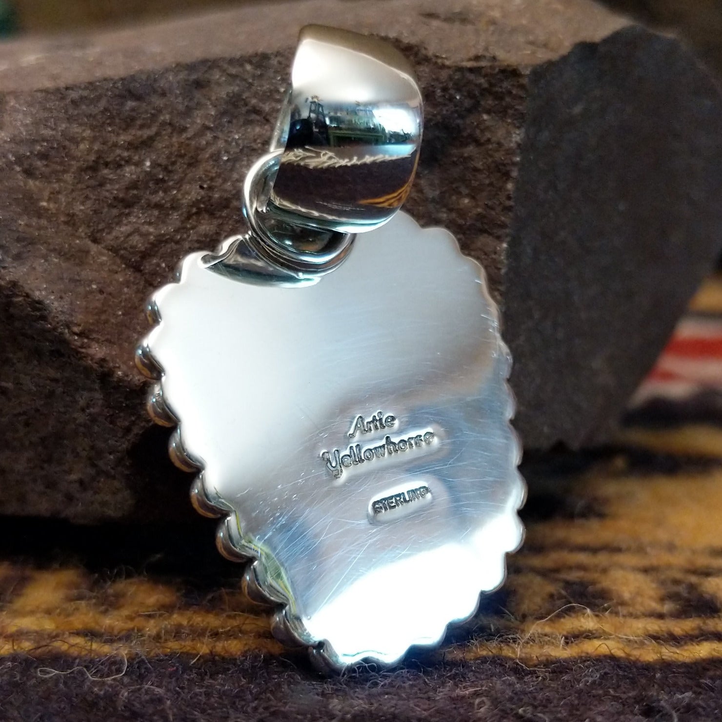 Handcrafted sterling silver pendant by Artie Yellowhorse featuring a red spiny oyster shell with dotted silver detailing in a Southwestern Native American design. Back view showcasing artisan and Sterling Silver stamp.