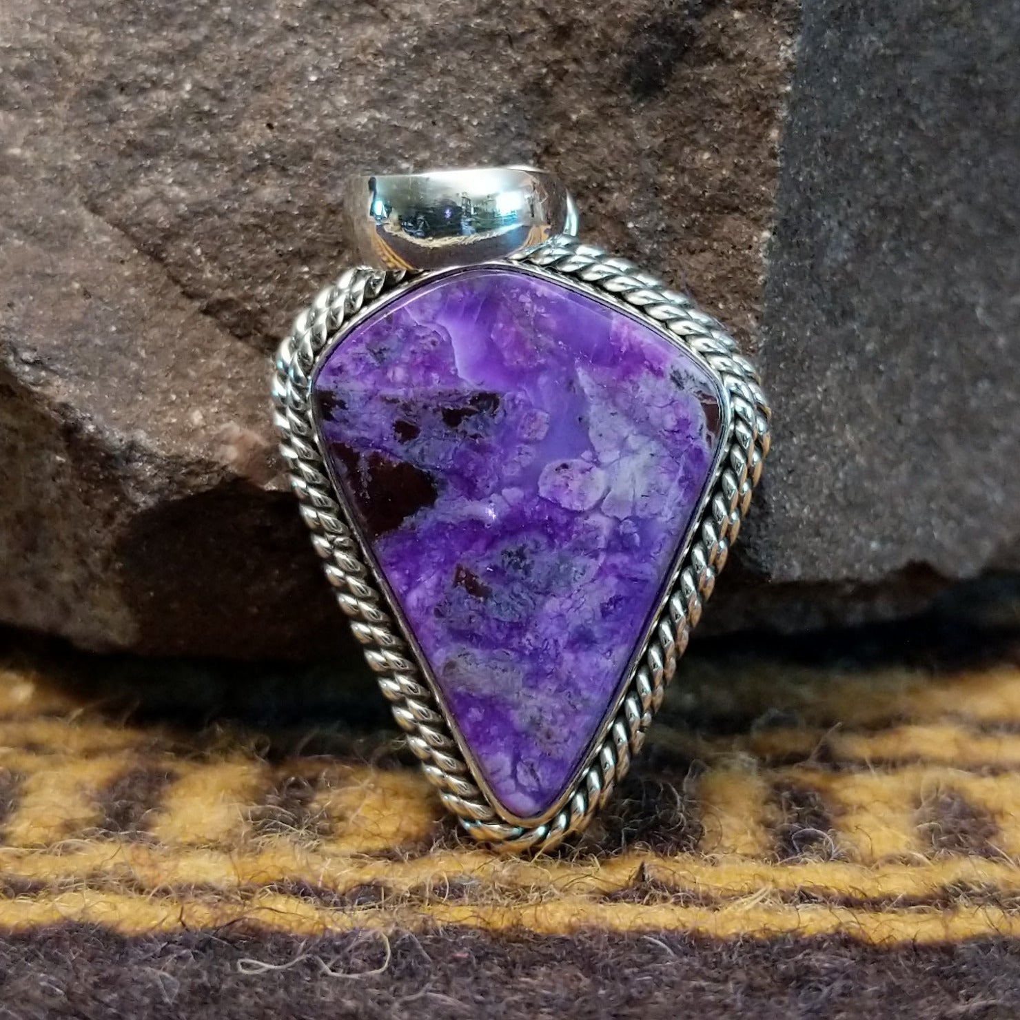 Handcrafted sterling silver pendant by Artie Yellowhorse featuring a deep purple sugilite stone in a polished Southwestern Native American design.