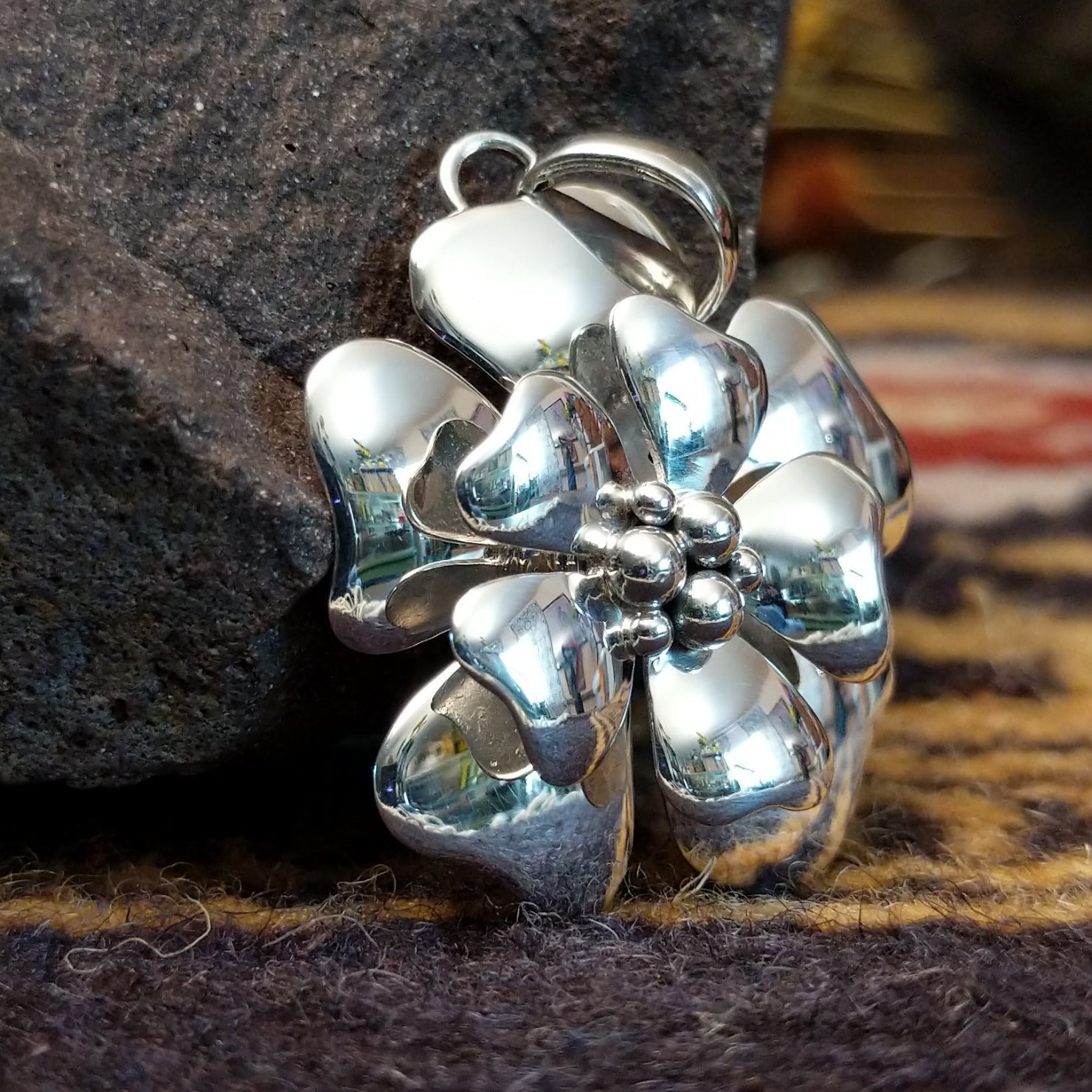 Handcrafted sterling silver pendant by Artie Yellowhorse featuring a detailed dogwood flower design in a polished Southwestern Native American style. Side view.