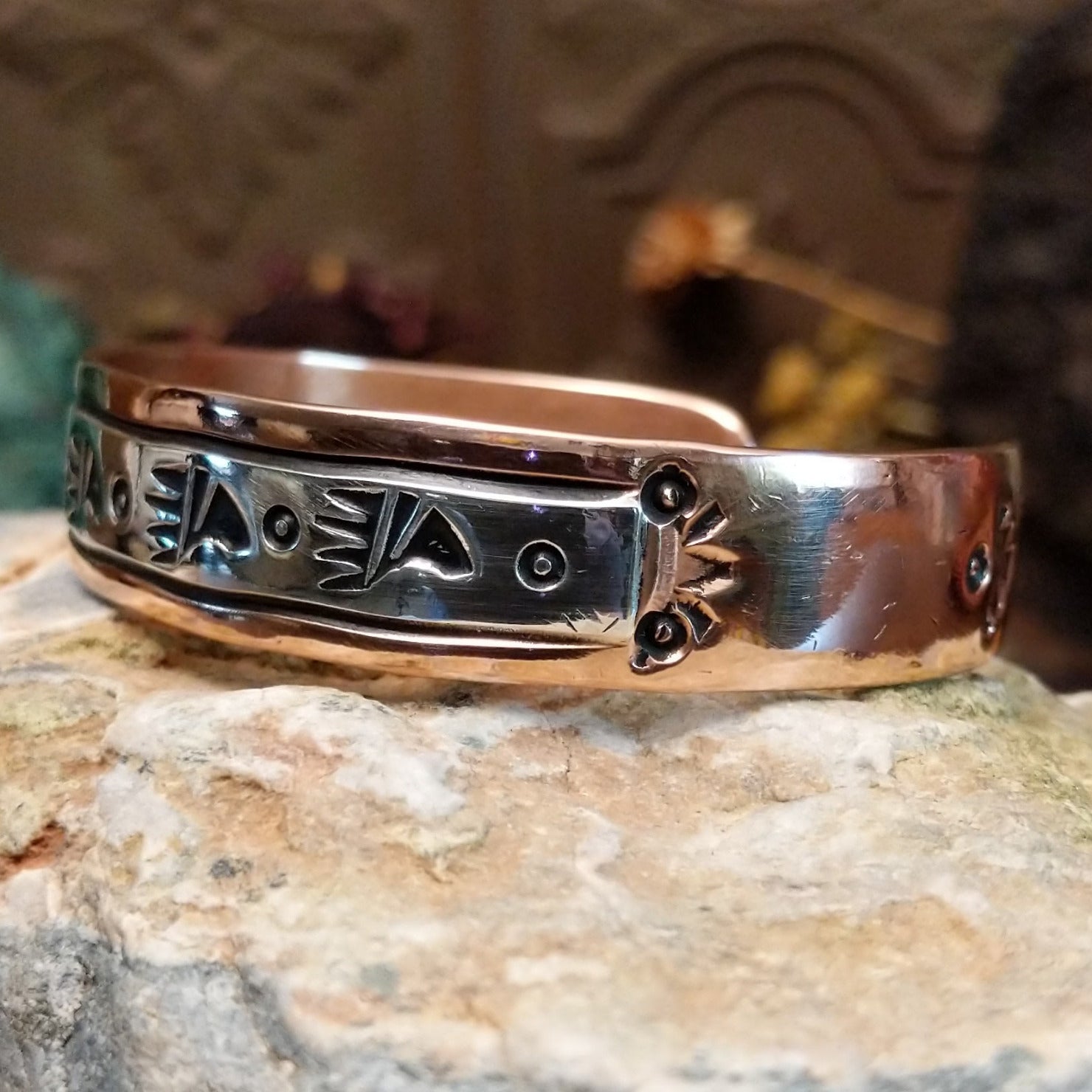 Handcrafted copper and sterling silver cuff bracelet by Navajo artisan Robert Little featuring bear paw stamped detailing in a traditional Southwestern design. Side view.
