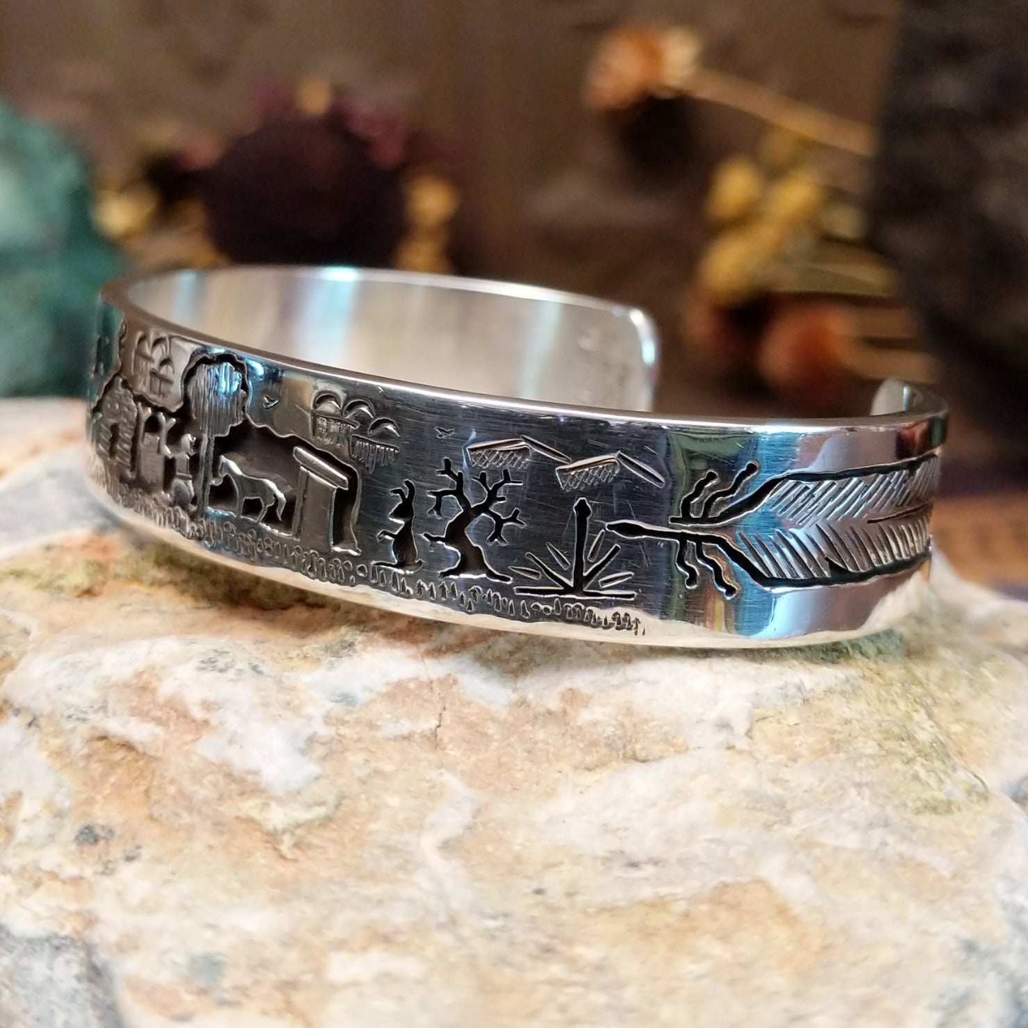Handcrafted sterling silver cuff bracelet by Navajo artist Gilbert Begay featuring an engraved landscape storyteller design with traditional Southwestern details. Side view.
