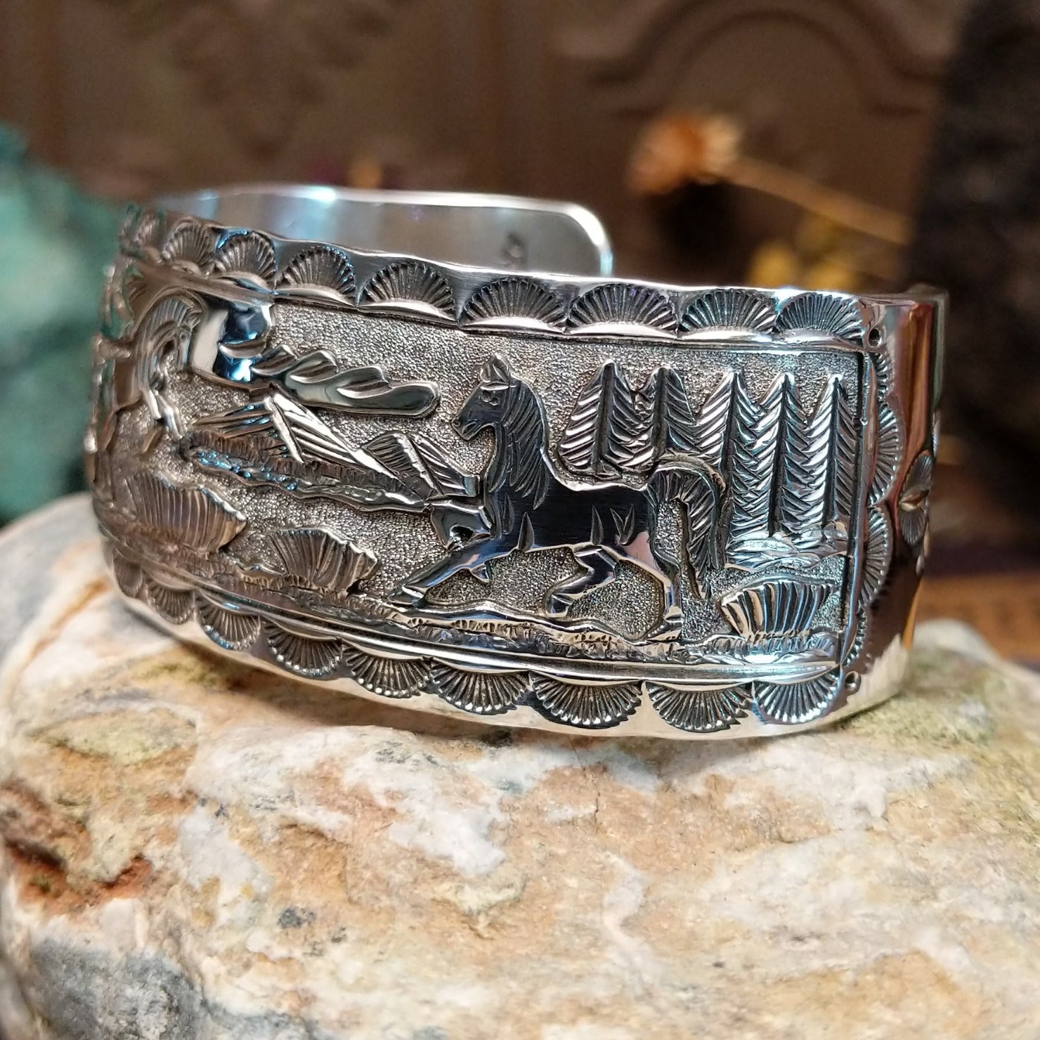 Handcrafted sterling silver cuff bracelet by Navajo artist June Delgarito featuring an engraved horse and landscape scene in a traditional Southwestern design. Side view.