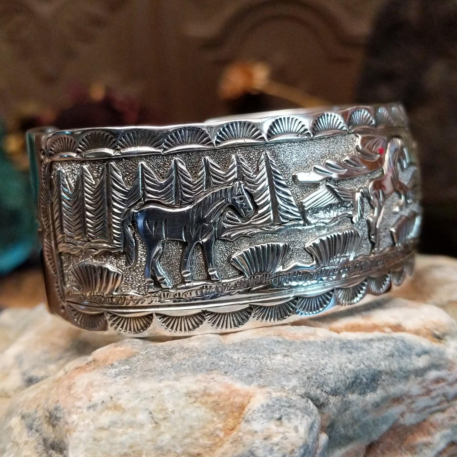 Handcrafted sterling silver cuff bracelet by Navajo artist June Delgarito featuring an engraved horse and landscape scene in a traditional Southwestern design. Side view.