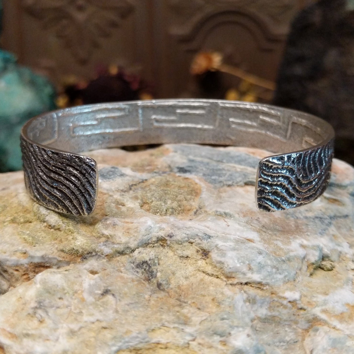 Handcrafted sterling silver cuff bracelet by Dino Garcia featuring a wavy tufa cast design with textured organic detailing in a Southwestern Native American style. Underside view.