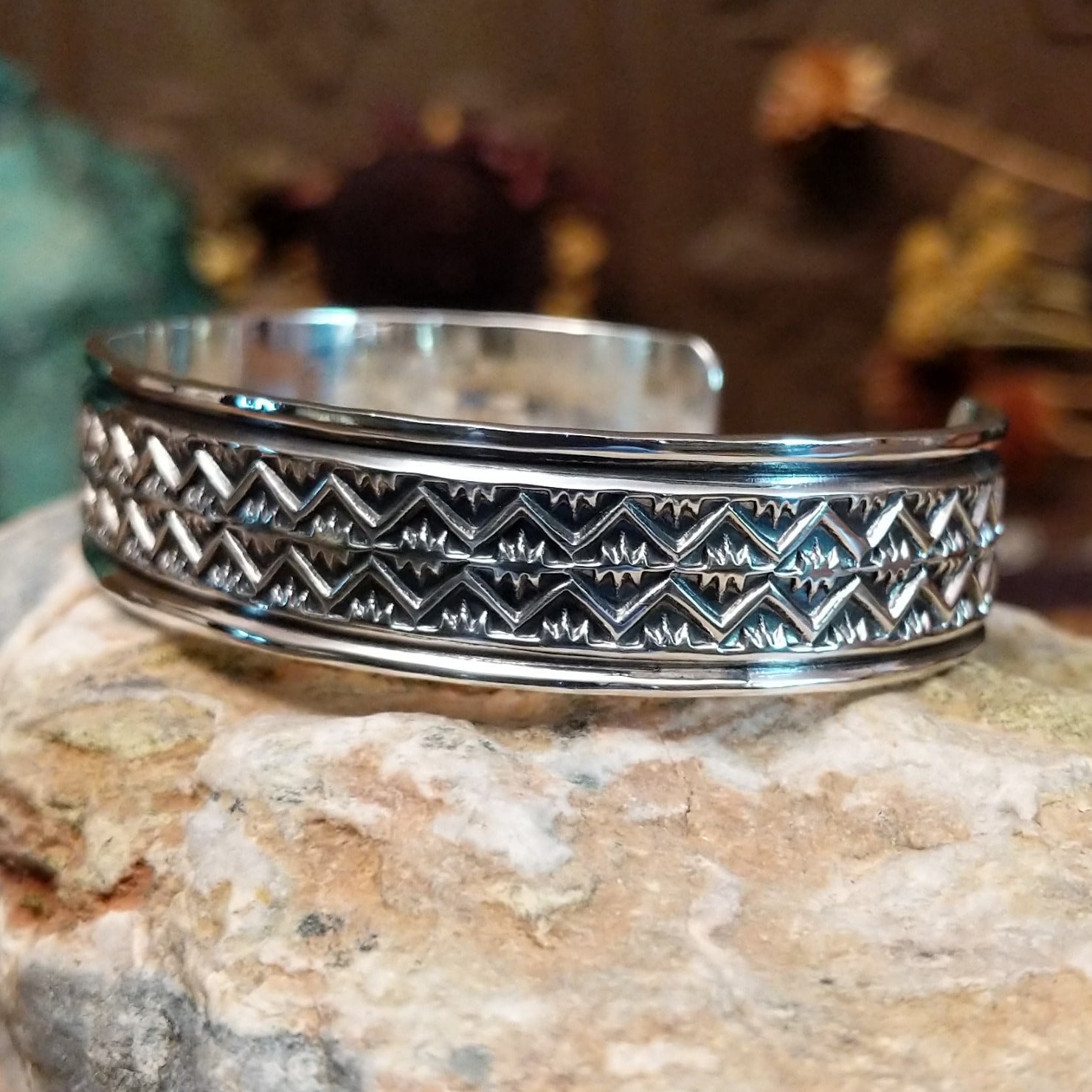 Handcrafted sterling silver cuff bracelet by Sunshine Reeves featuring diamond-stamped geometric detailing in a traditional Navajo Southwestern design. Side view.