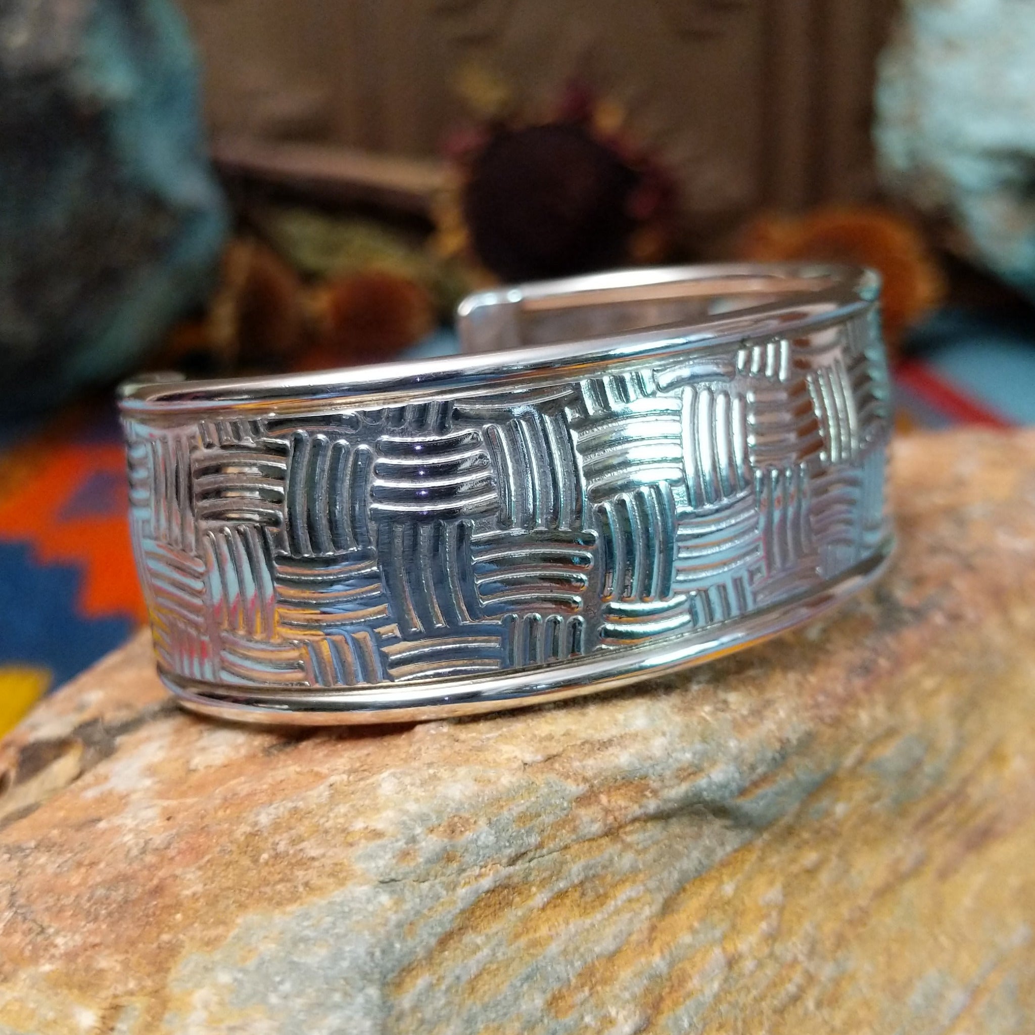 Wide silver cuff by Larry Joe with repeating curved line stampwork arranged in a woven pattern.